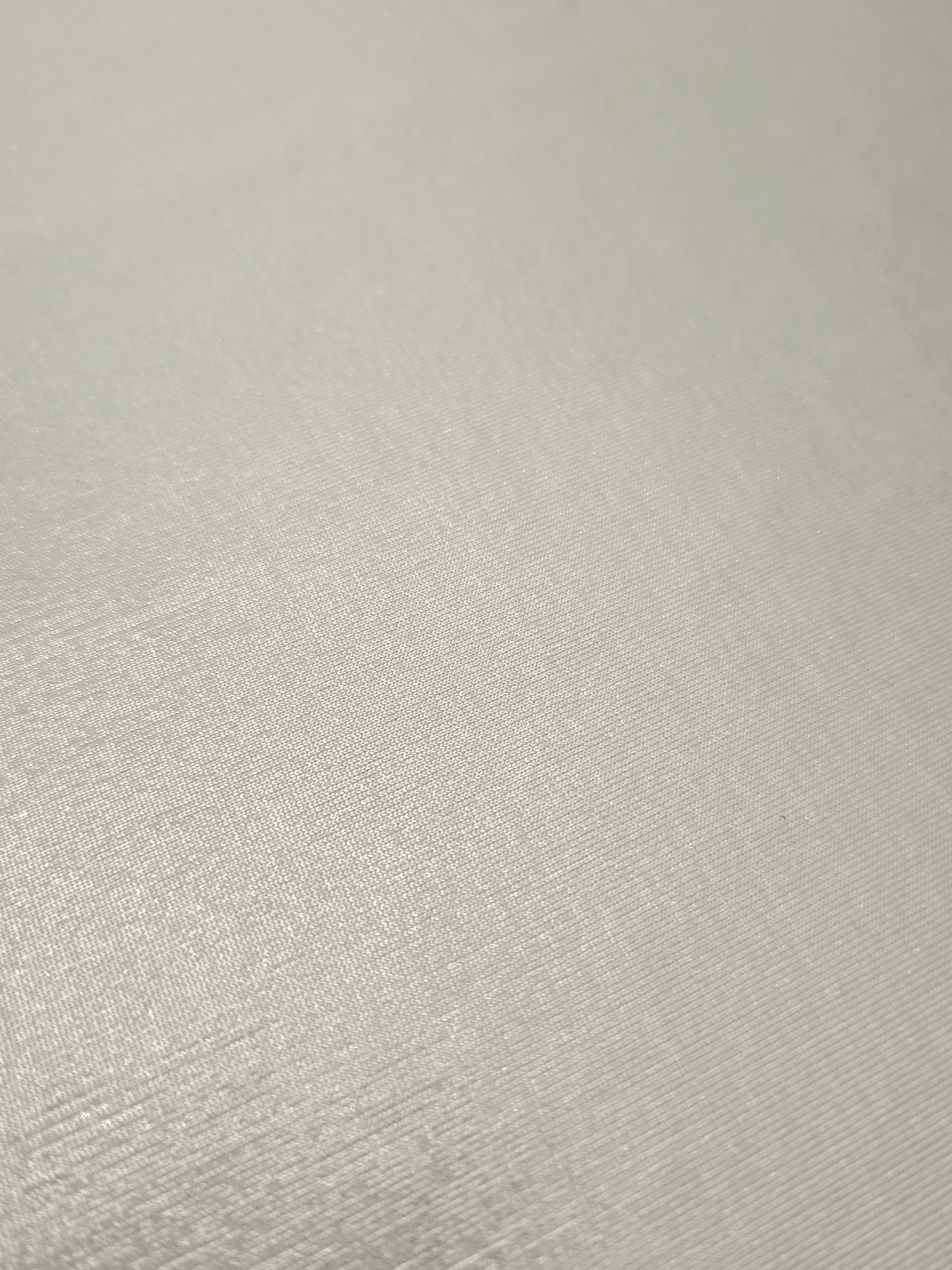 Detailed close-up of Pearl Ivory foiled spandex fabric showing its luminous metallic surface and fine reflective texture