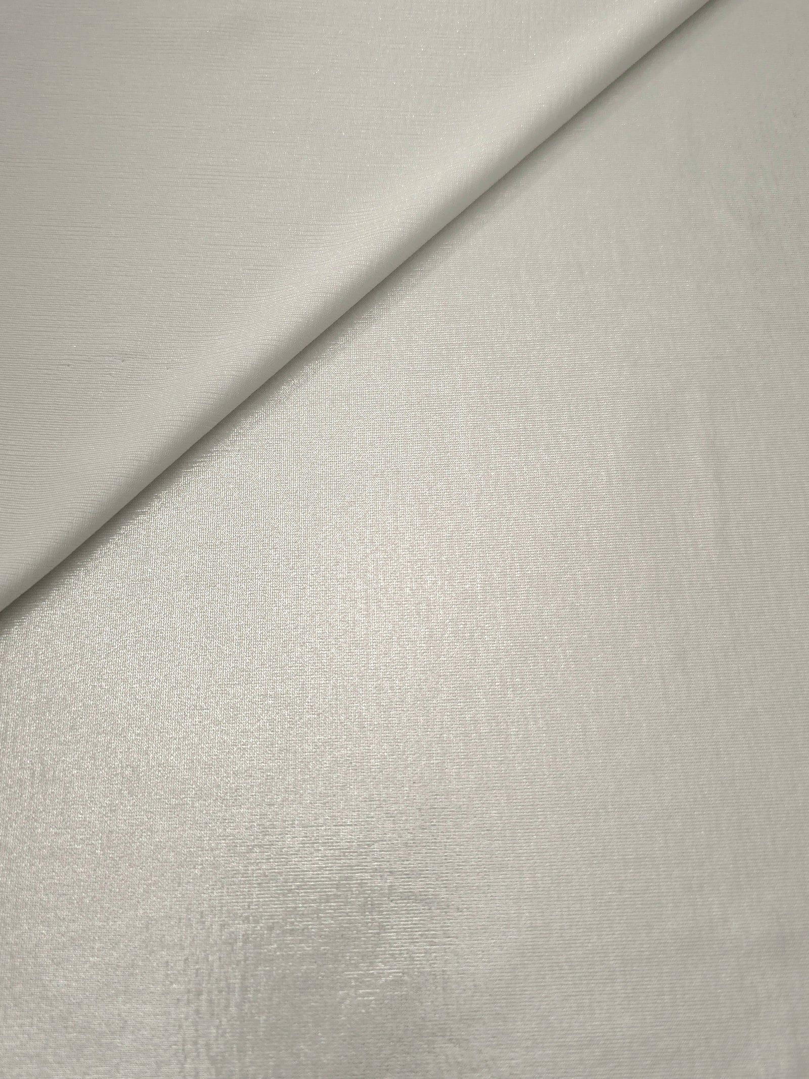 Pearl Ivory foiled stretch fabric in a gentle fold, showing metallic shimmer and flexibility for partywear and performance fashion