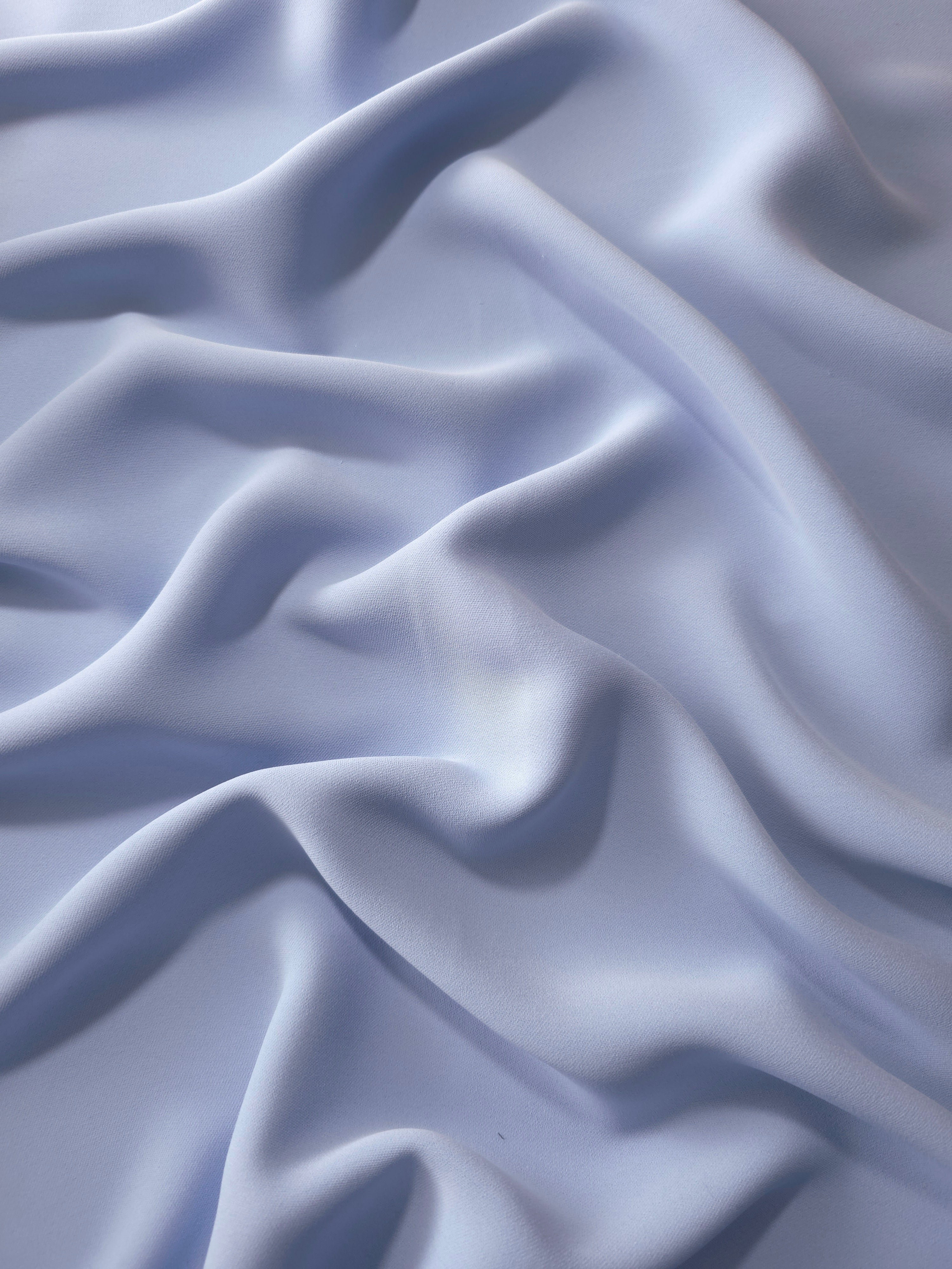 Draped folds of Periwinkle Blue polyester crepe showing opaque coverage and fluid movement for garment making