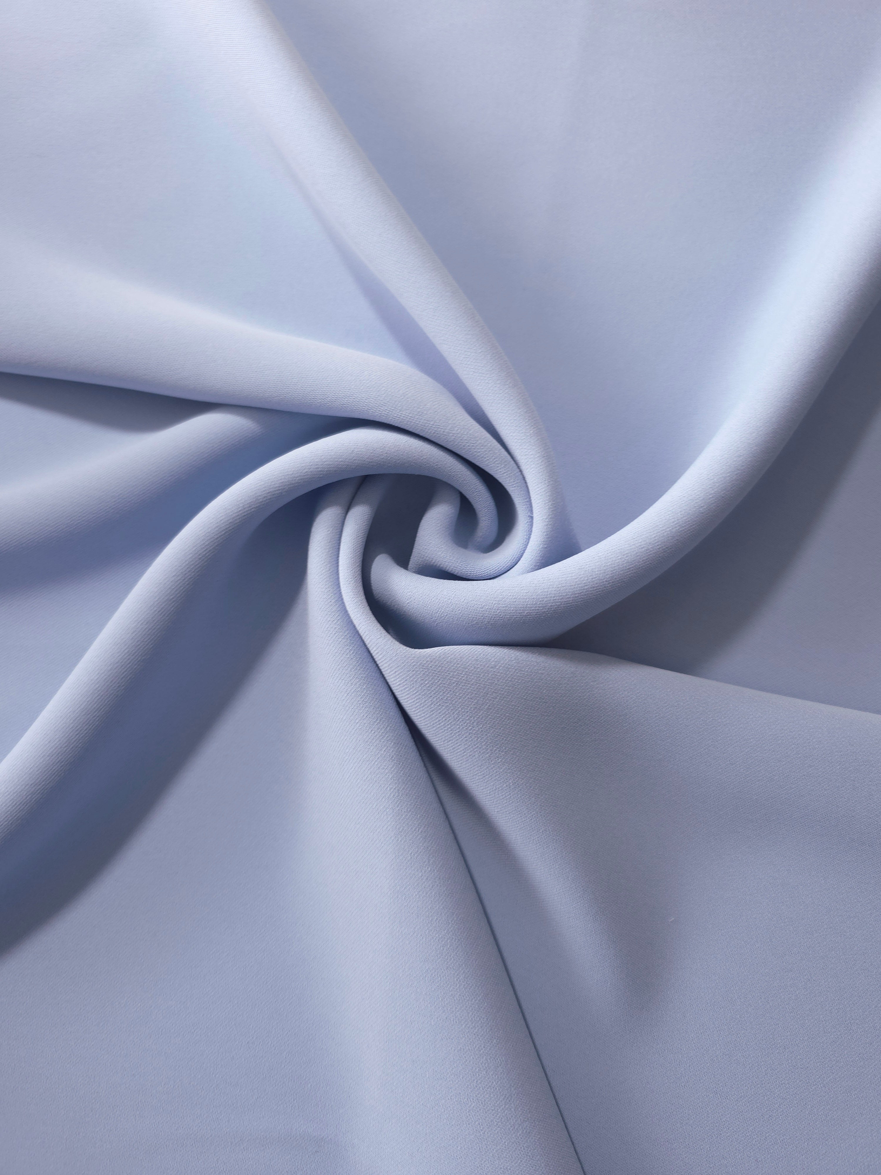 Periwinkle Blue silky-soft polyester crepe styled in a swirl to show fluid dressmaking drape and movement