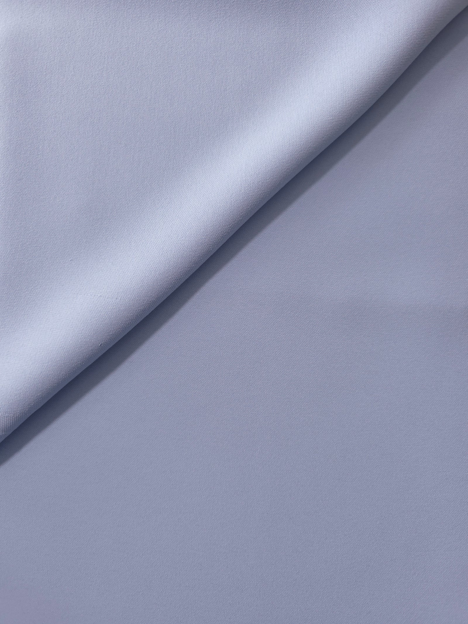 Periwinkle Blue opaque Korean polyester crepe in a soft fold, showing flowing drape for garment making