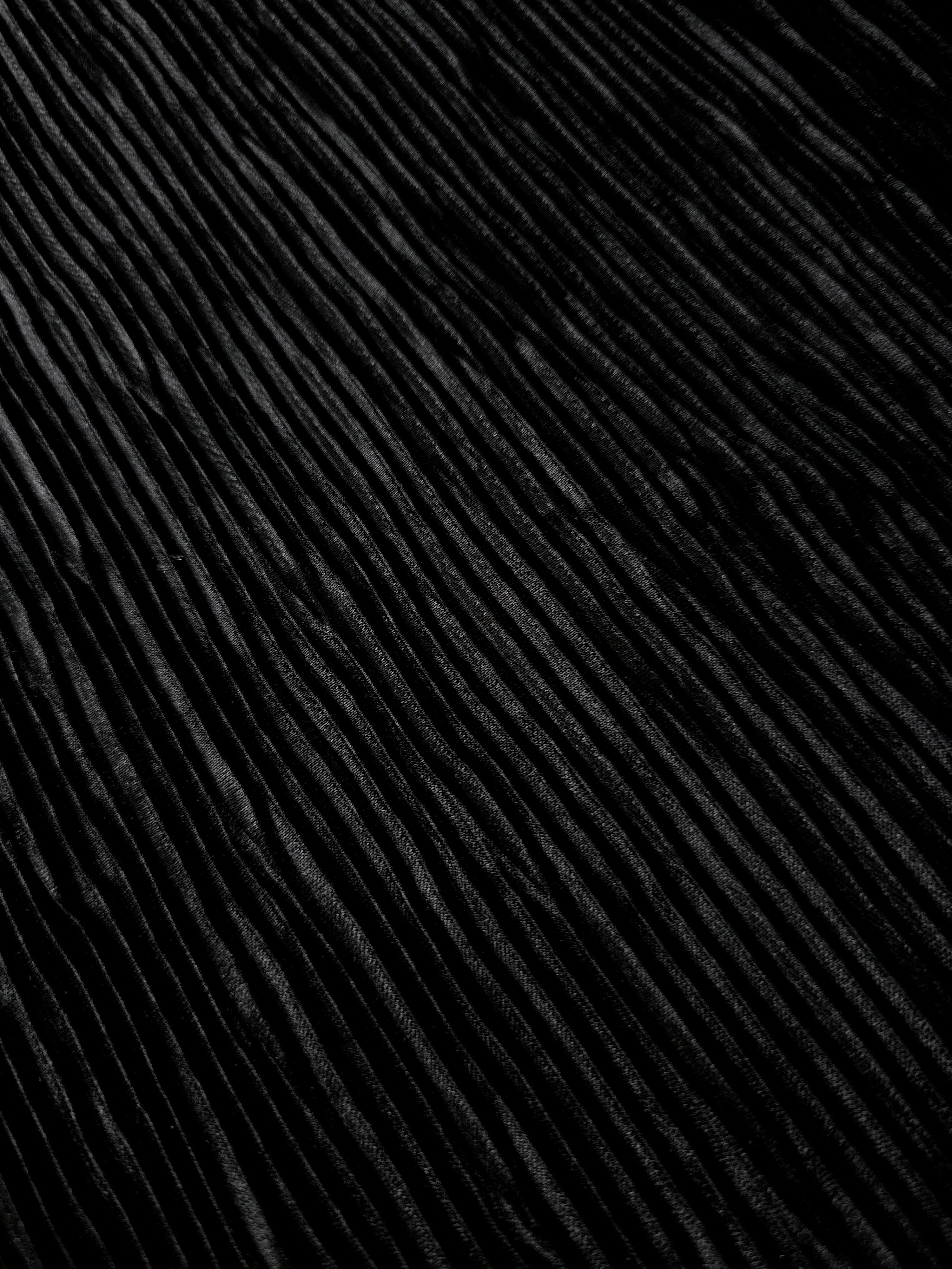 Jet black micro pleated stretch bodre satin fabric diagonal close-up