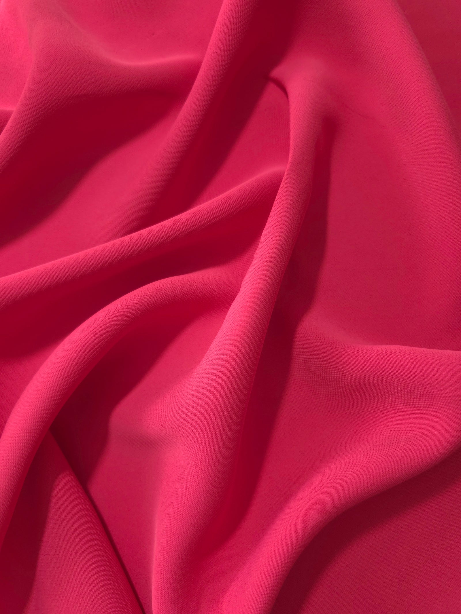Raspberry Red Korean polyester dress fabric shown in draped folds for occasionwear, blouses and dresses
