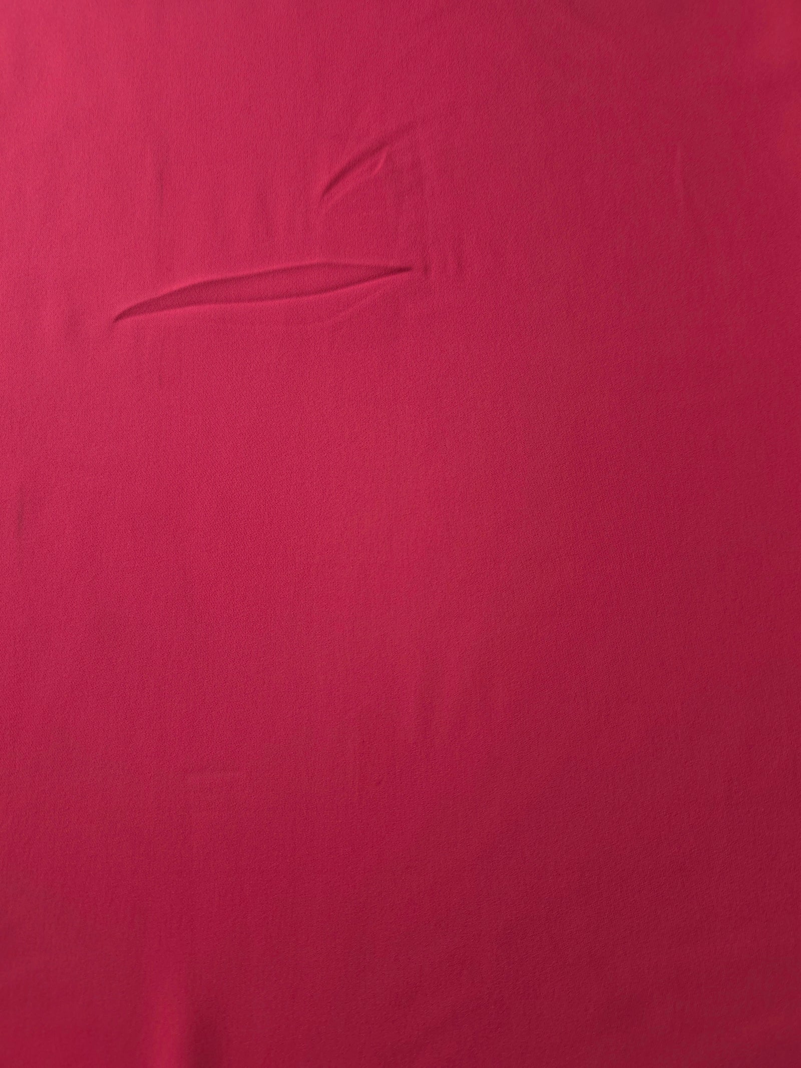 Surface view of Raspberry Red 205 GSM polyester crepe, opaque Korean dress fabric with a smooth woven finish