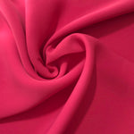 Flowing swirl of Raspberry Red Korean polyester crepe showing soft drape for blouses, dresses and abayas