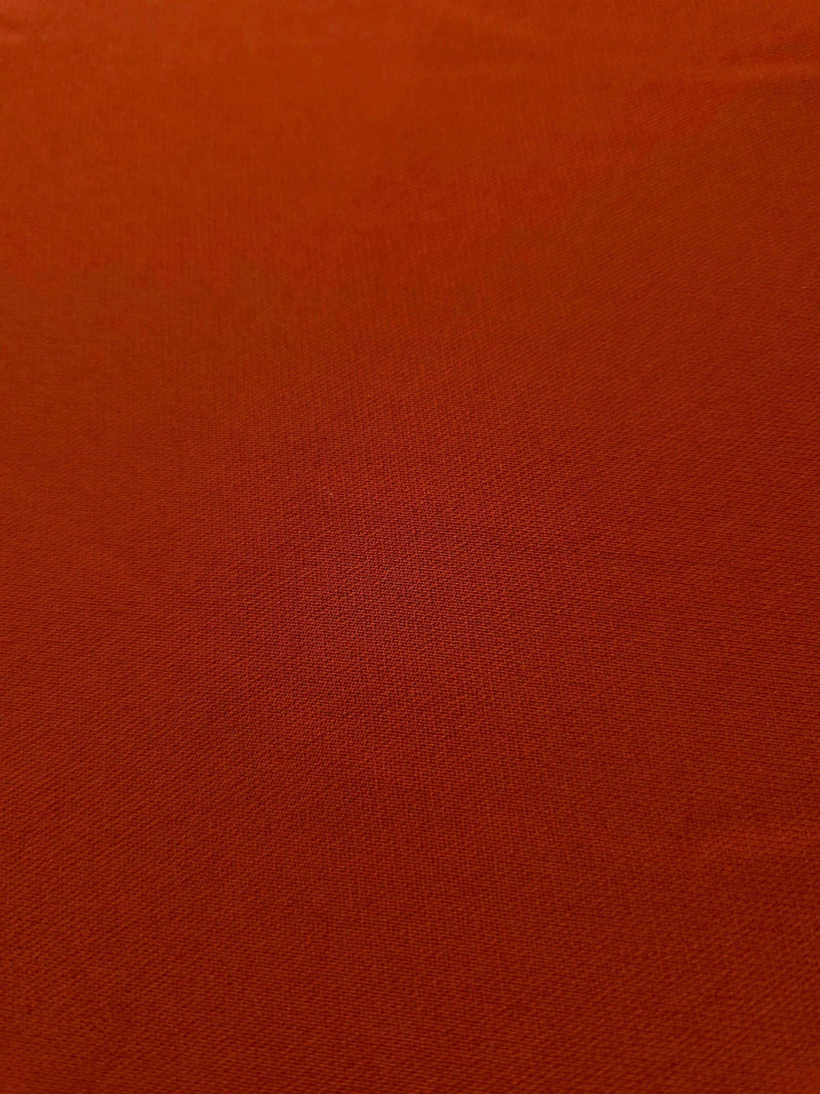 Close woven detail of Rust Orange 100% polyester Korean crepe showing its smooth texture and soft finish