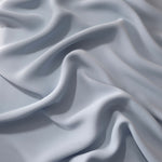 Silver Blue Korean polyester dress fabric shown in draped folds for occasionwear, blouses and dresses