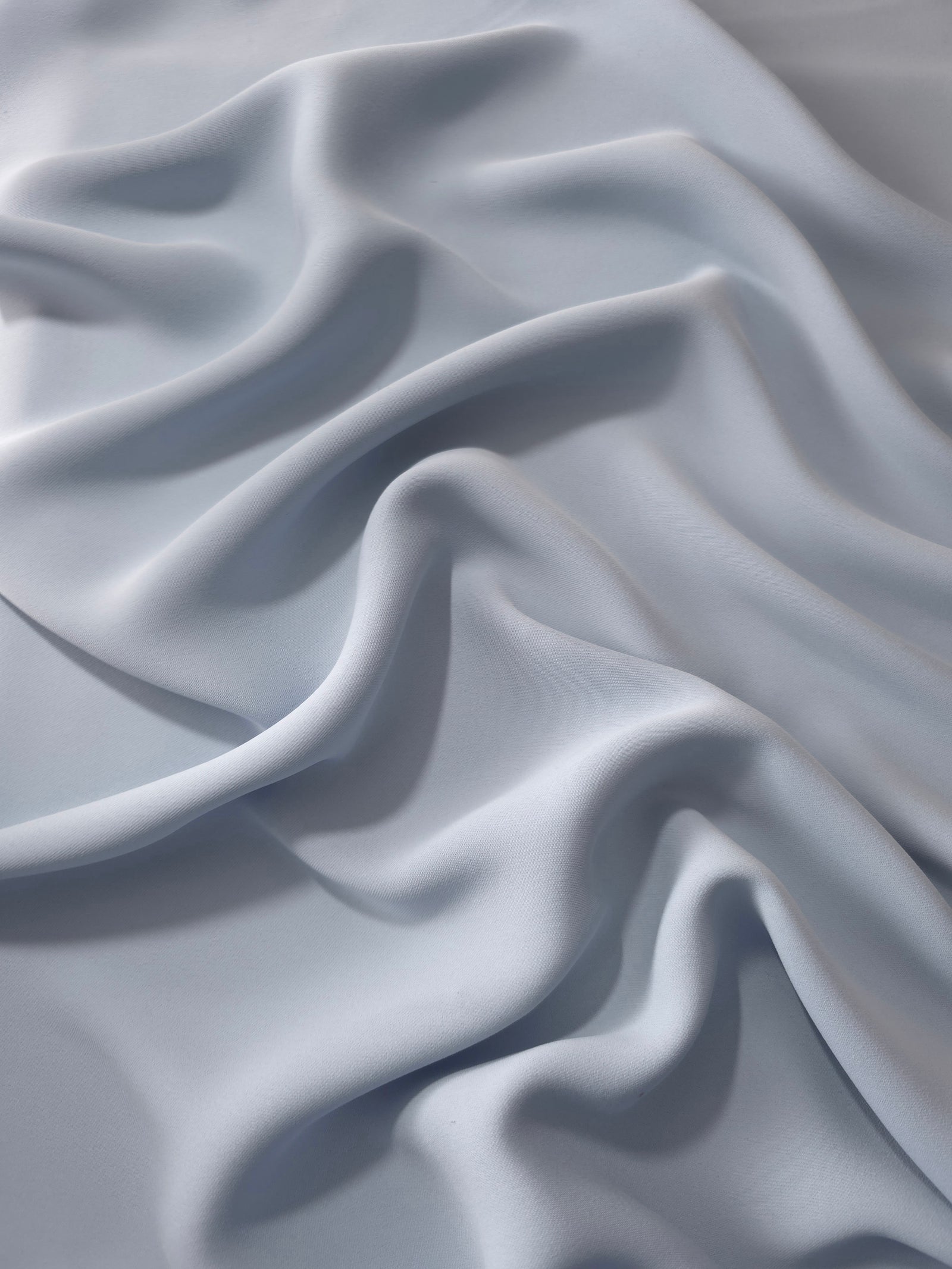 Silver Blue Korean polyester dress fabric shown in draped folds for occasionwear, blouses and dresses