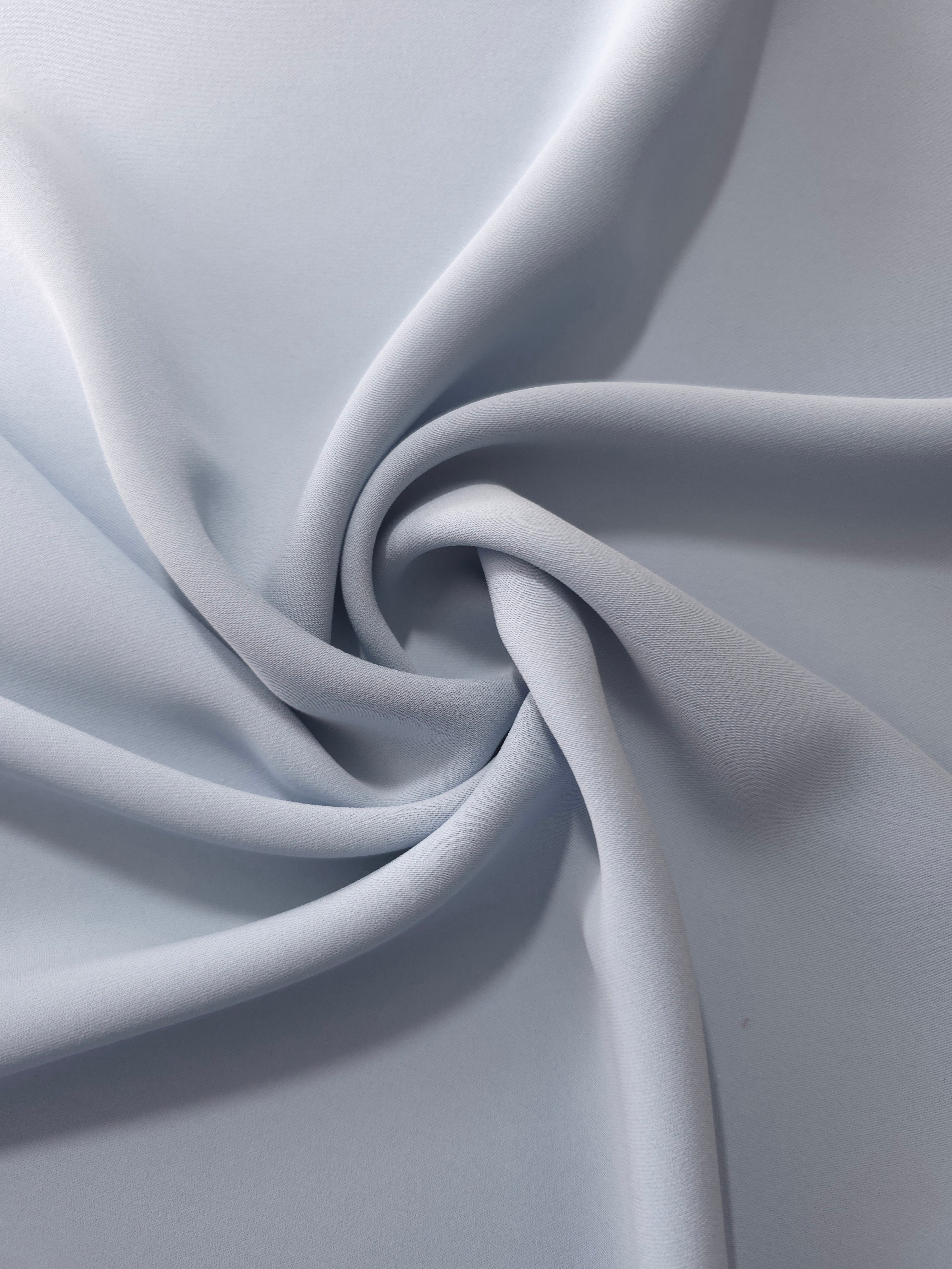 Flowing swirl of Silver Blue Korean polyester crepe showing soft drape for blouses, dresses and abayas
