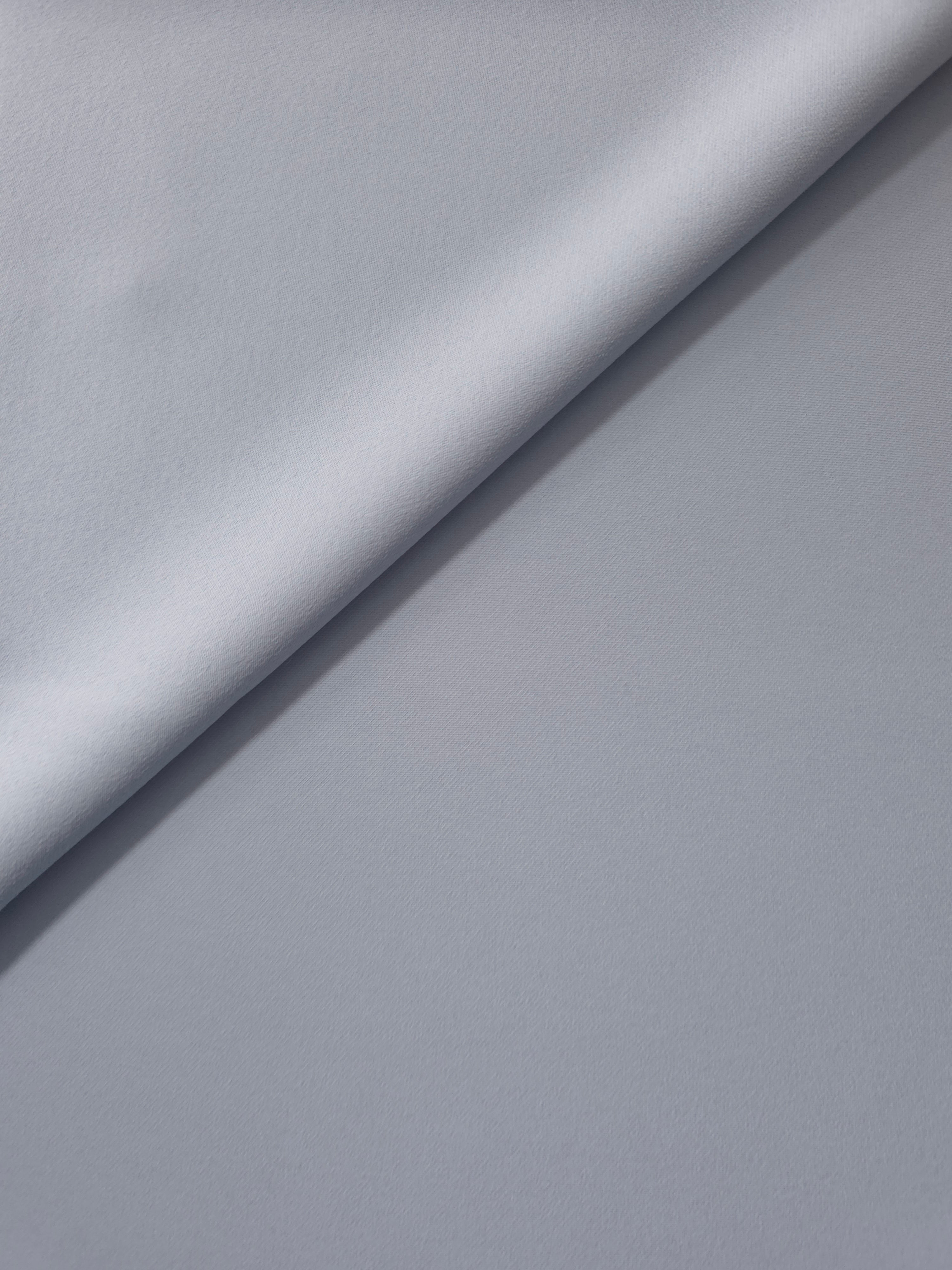 Loose fold of Silver Blue polyester crepe showing smooth fluid drape for dresses, skirts and soft tailoring