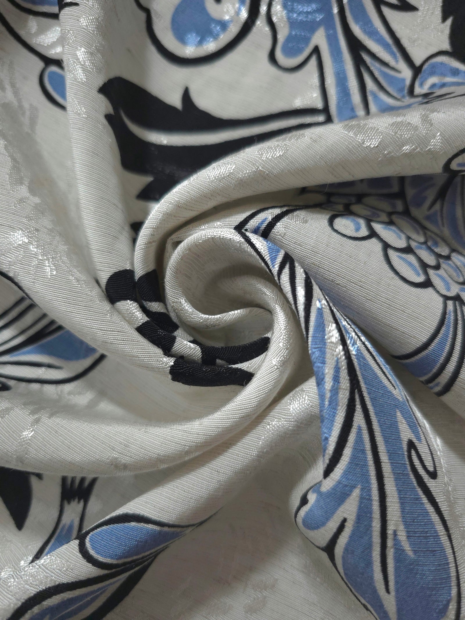Blue sketch floral linen-look jacquard fabric folded view showing apparel drape and woven texture.