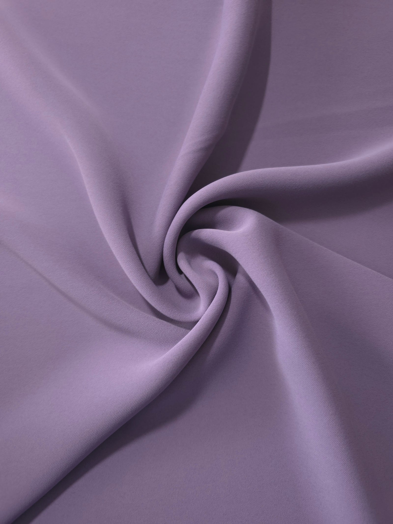 Flowing swirl of Smoky Lavender Korean polyester crepe showing soft drape for blouses, dresses and abayas