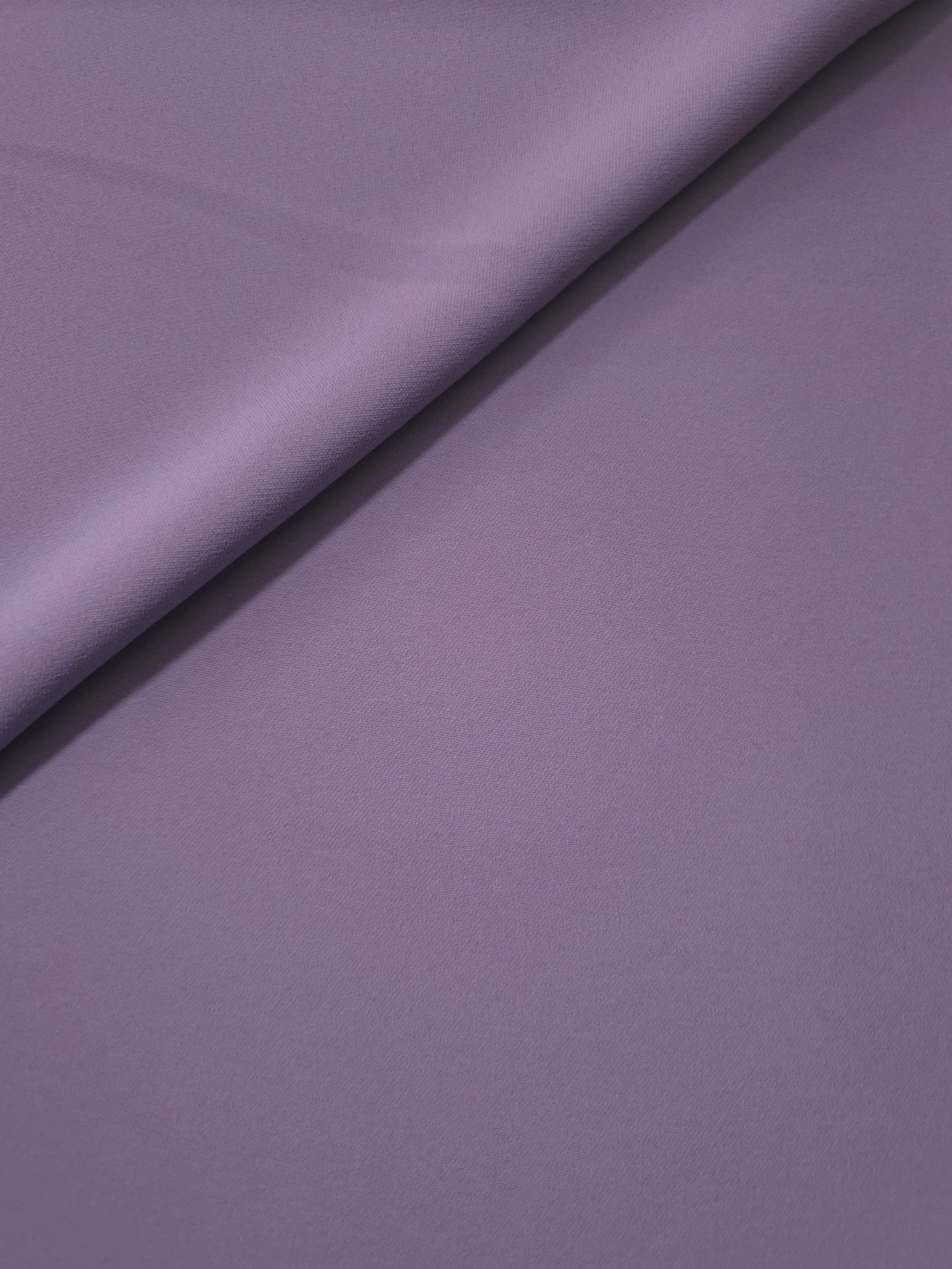 Loose fold of Smoky Lavender polyester crepe showing smooth fluid drape for dresses, skirts and soft tailoring