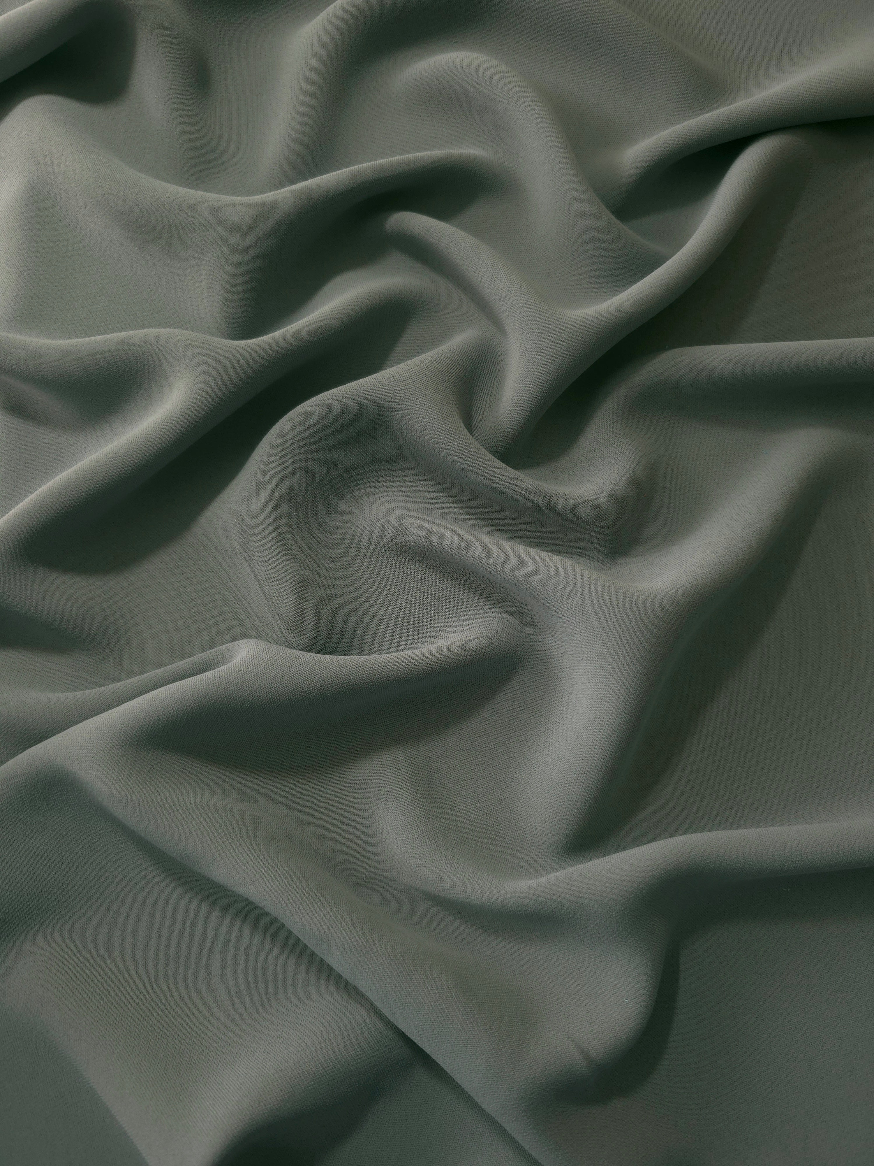Smoky Sage Green polyester crepe in long draped folds, showing flowing coverage for abayas and modest fashion