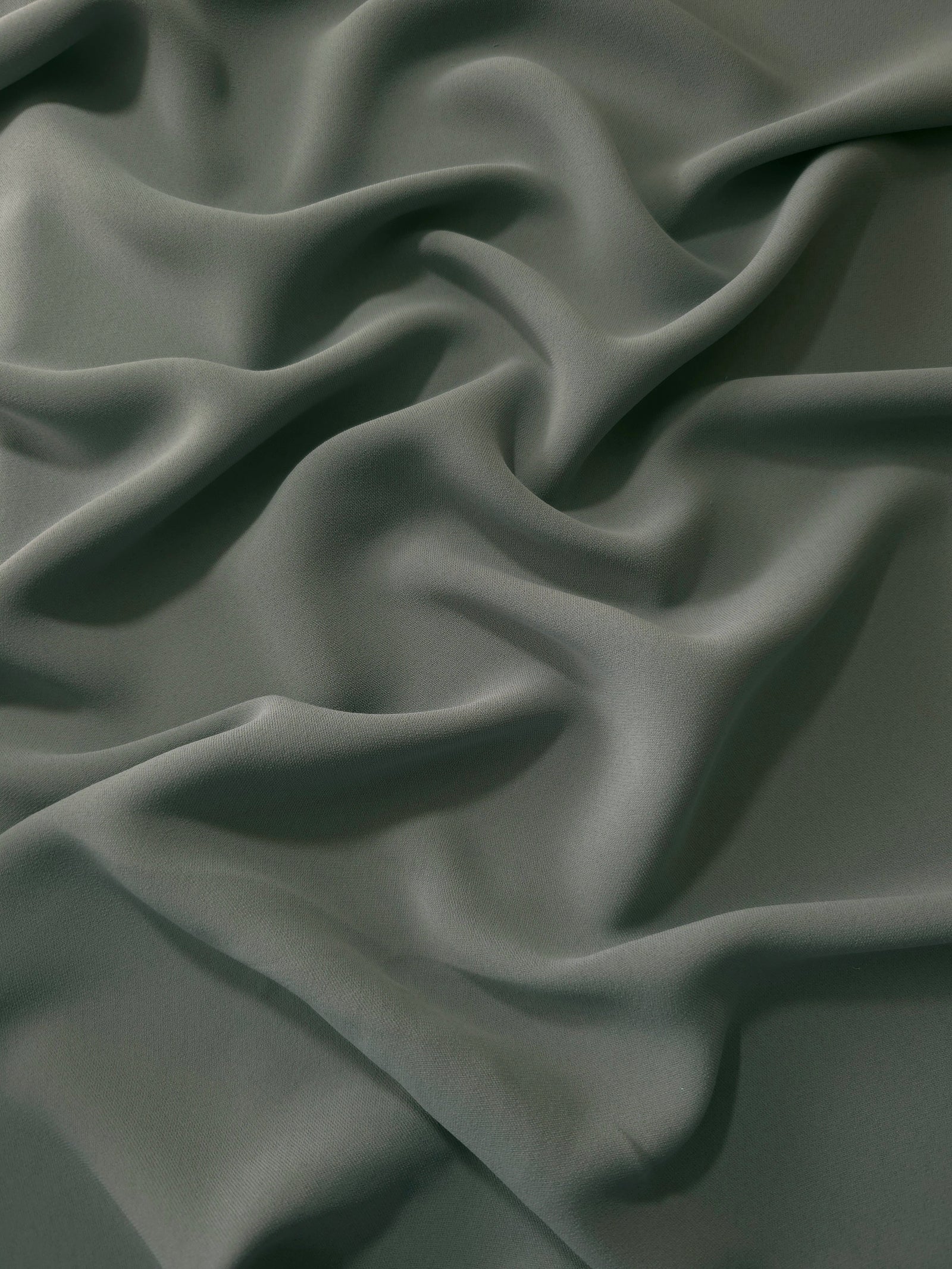 Smoky Sage Green polyester crepe in long draped folds, showing flowing coverage for abayas and modest fashion