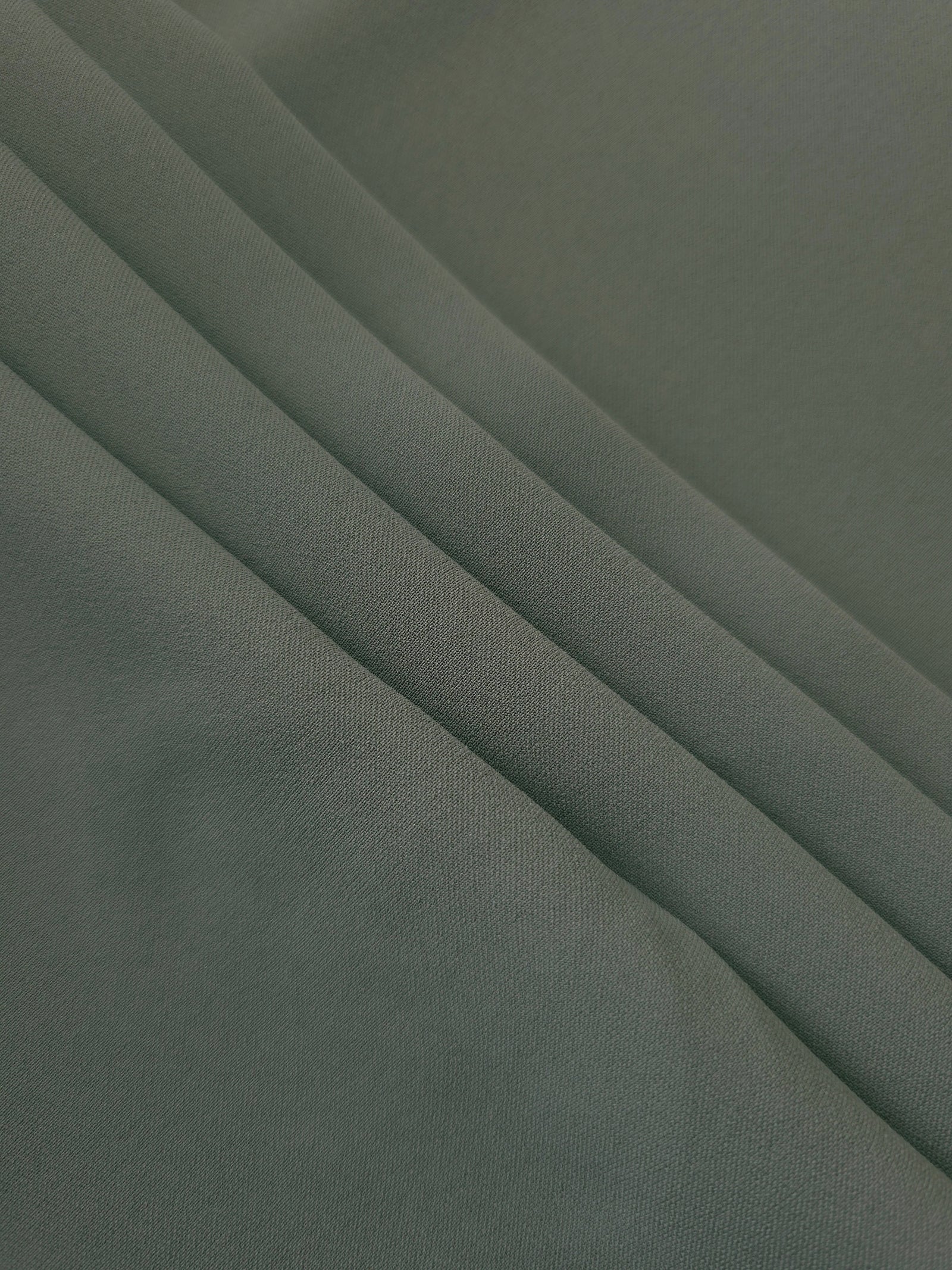 Smoky Sage Green Korean crepe in layered folds, showing soft structure and slight mechanical stretch for skirts
