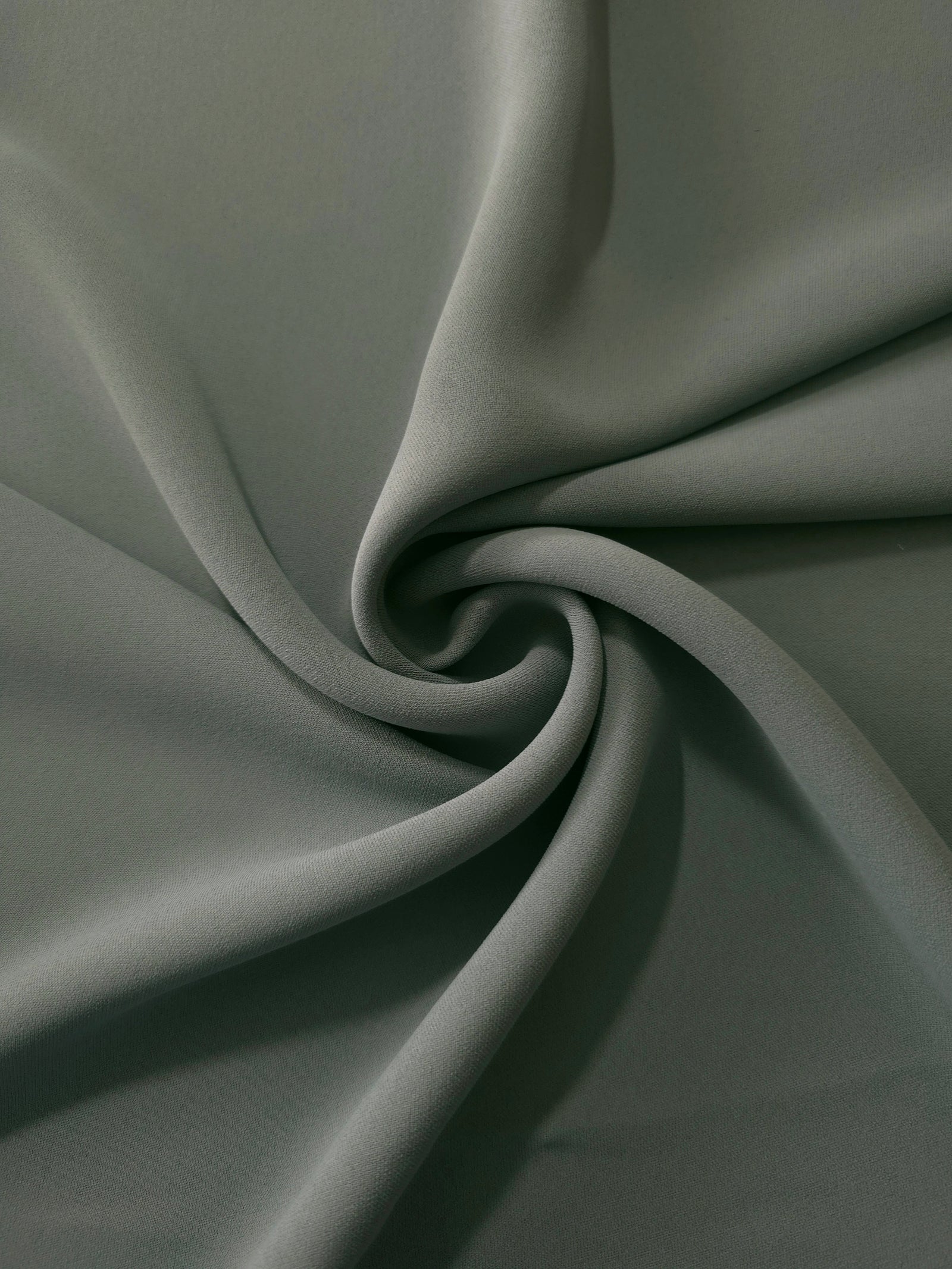 Swirled Smoky Sage Green Korean crepe showing fluid movement and silky drape for dresses and occasionwear