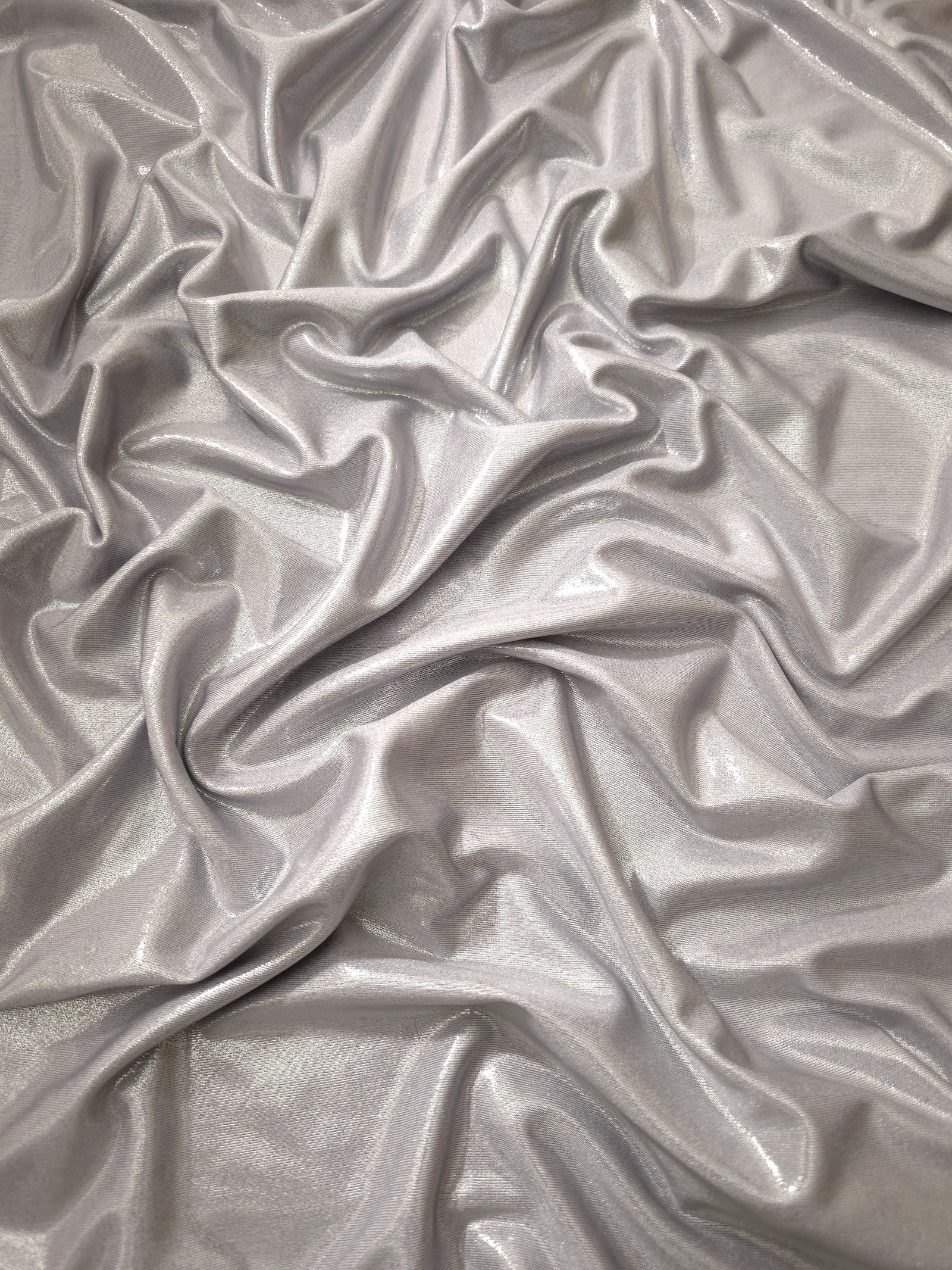 Draped Soft Silver Gray metallic foiled spandex showing reflective folds and flexible flow for dresses, stagewear and occasion looks