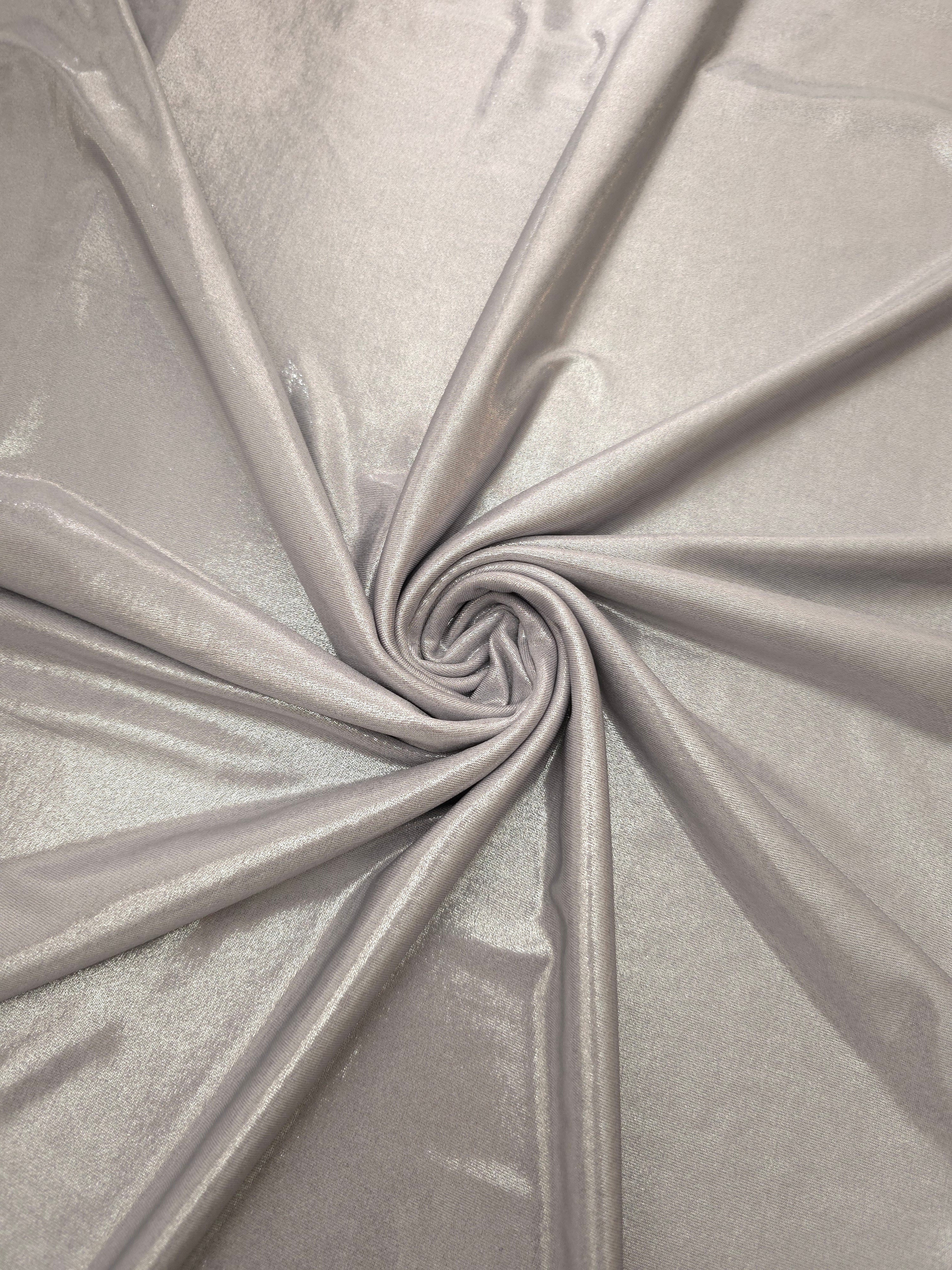 Soft Silver Gray shimmer foiled stretch fabric arranged in a swirl, highlighting movement and reflective finish for performancewear