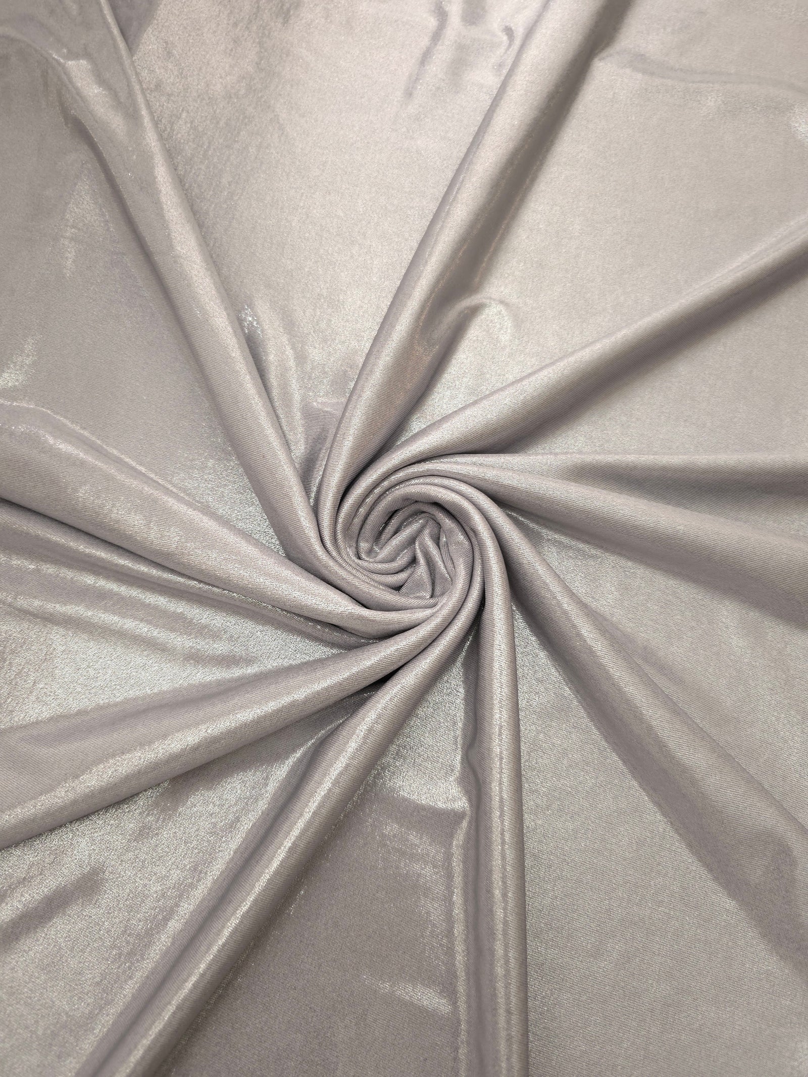 Soft Silver Gray shimmer foiled stretch fabric arranged in a swirl, highlighting movement and reflective finish for performancewear