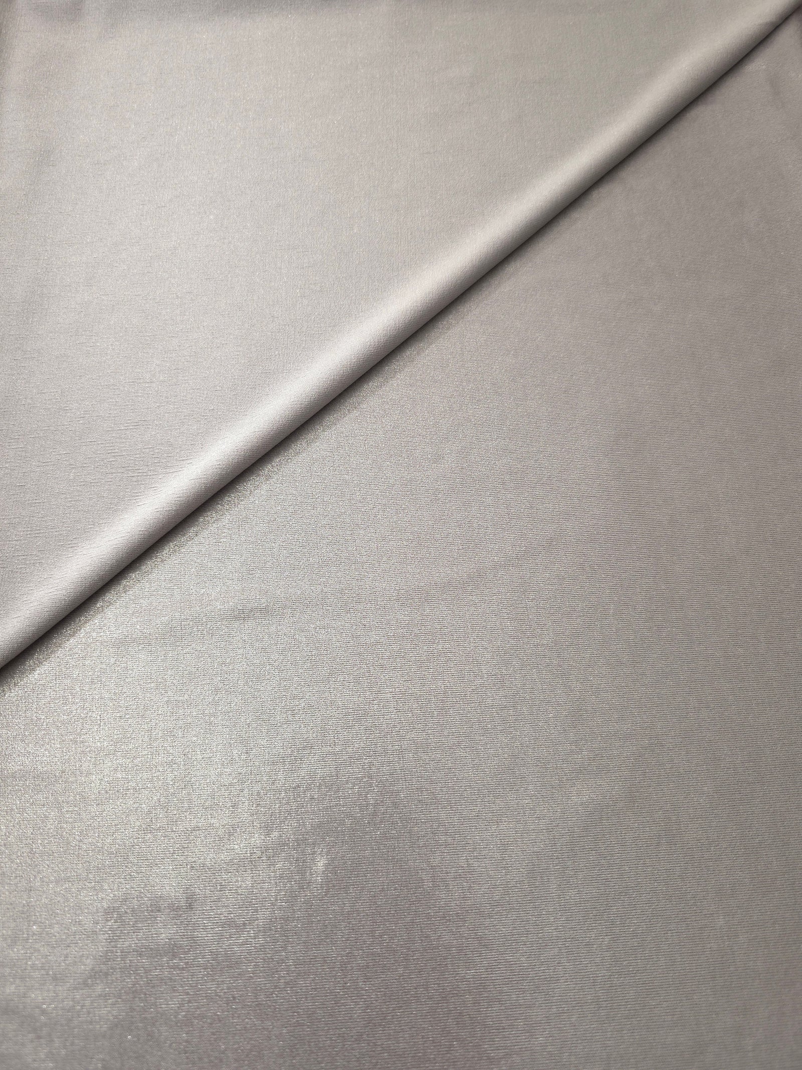 Soft Silver Gray shimmer spandex in a soft fold, showing metallic foil sheen and flexible drape for tops, skirts and costumes