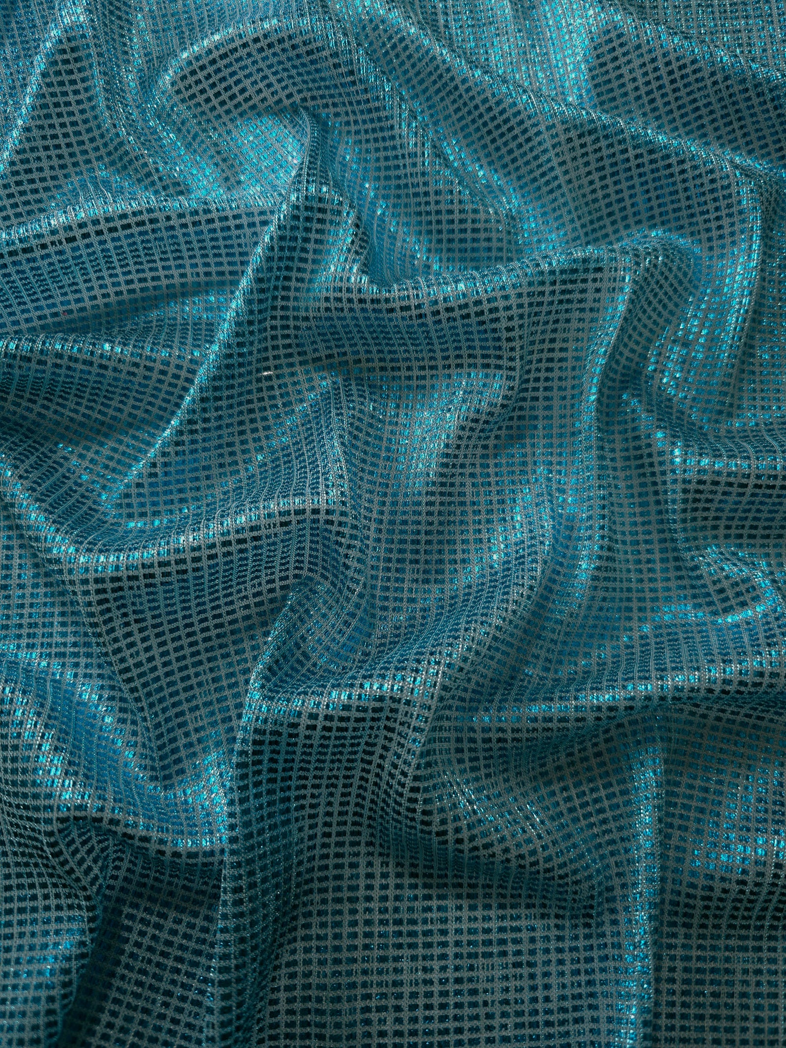 Draped Aqua Teal Sheer Square Shimmer Stretch Tulle Fabric showing a geometric reflective grid across fluid folds
