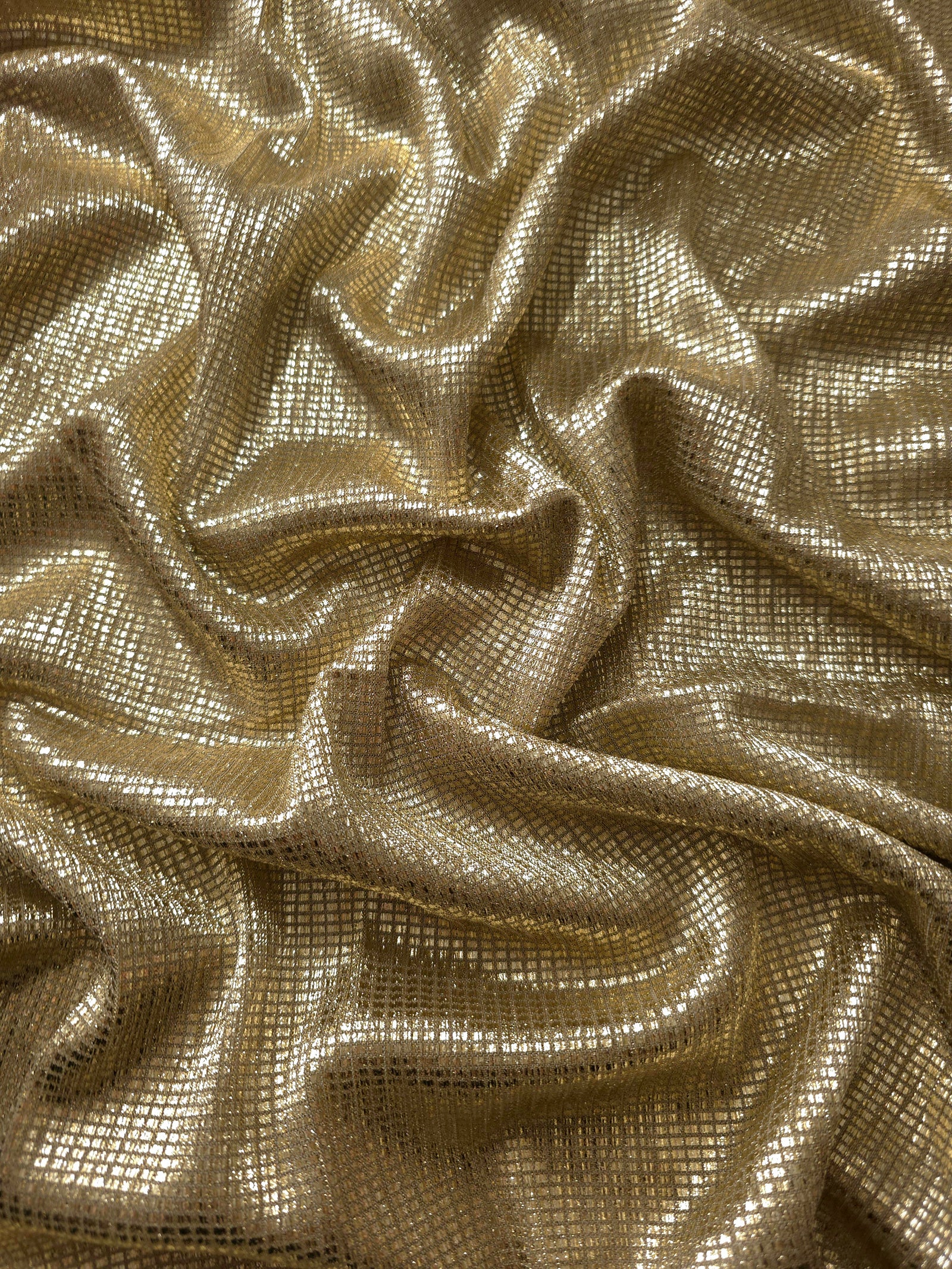 Draped Champagne Gold Sheer Square Shimmer Stretch Tulle Fabric showing a geometric reflective grid across fluid folds