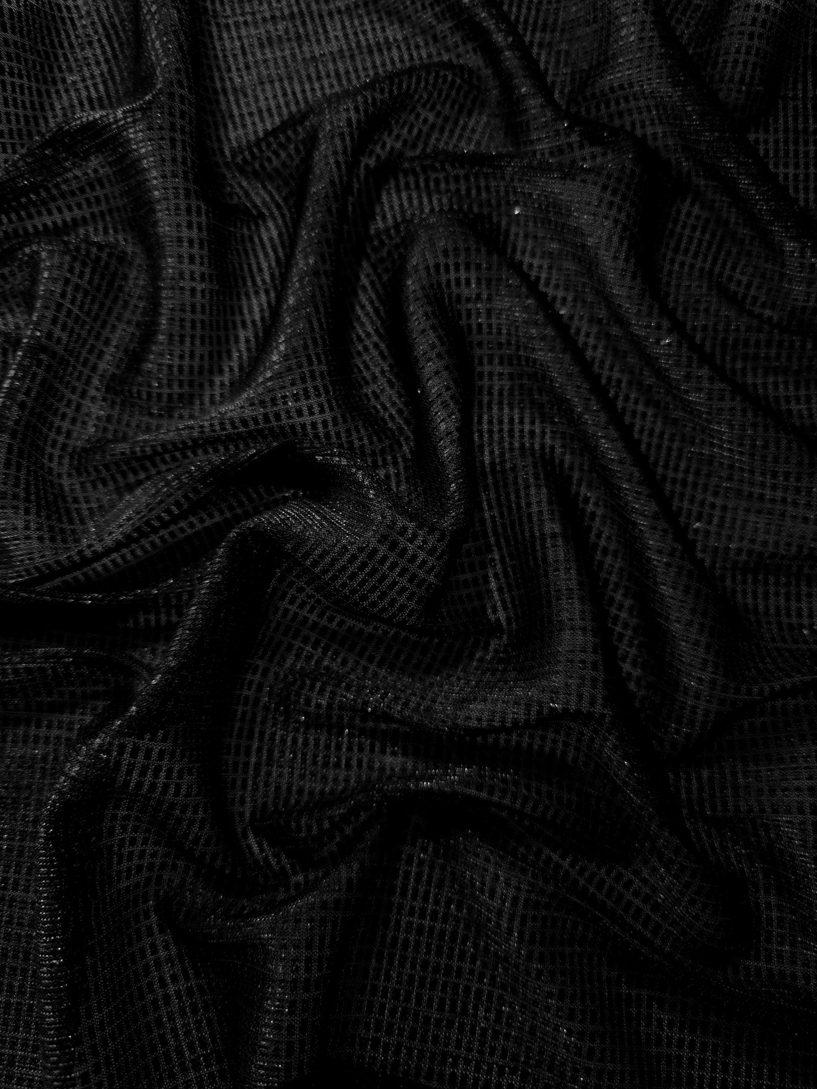 Draped Jet Black Sheer Square Shimmer Stretch Tulle Fabric showing a geometric reflective grid across fluid folds