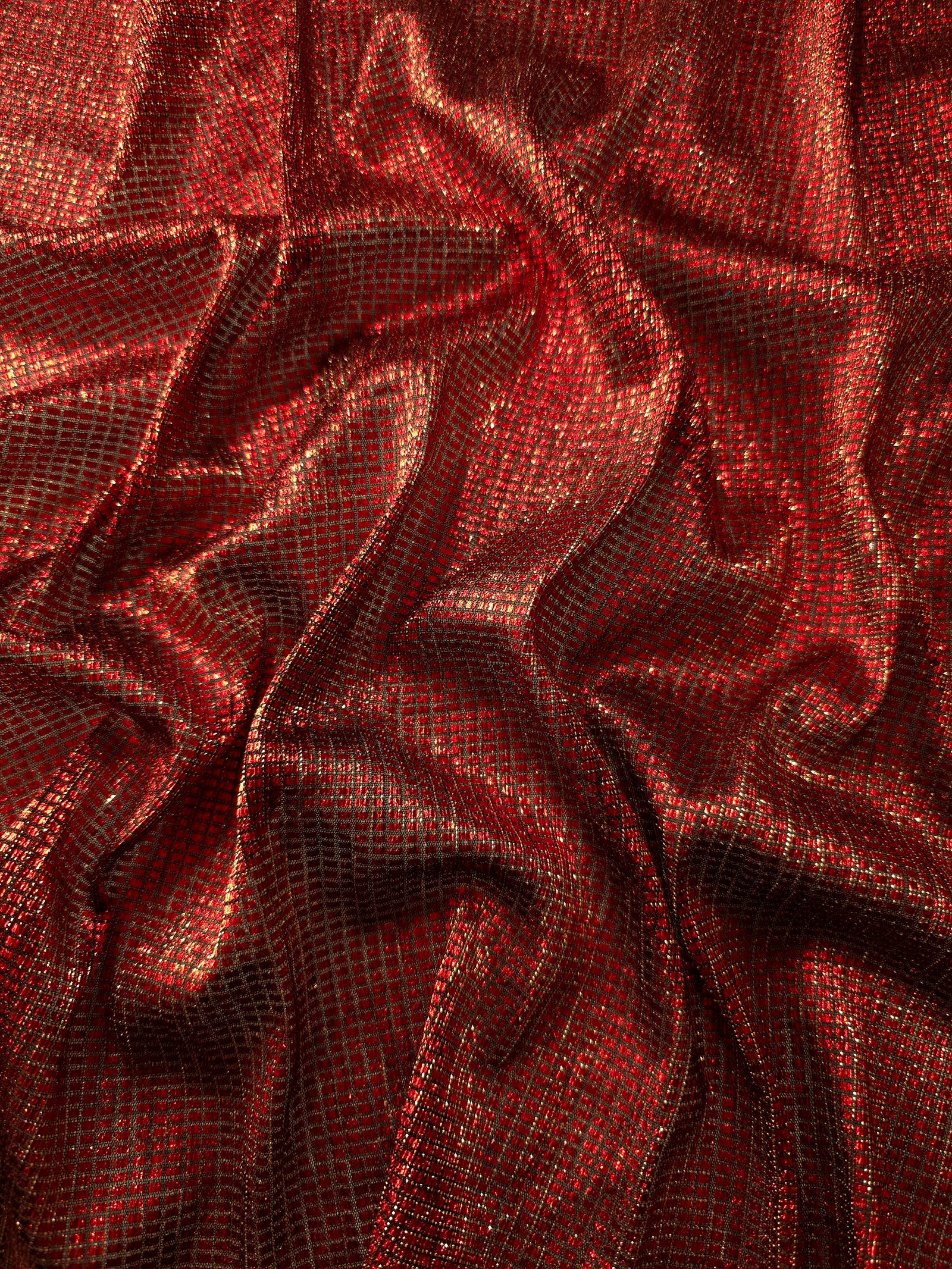 Draped Ruby Red Sheer Square Shimmer Stretch Tulle Fabric showing a geometric reflective grid across fluid folds