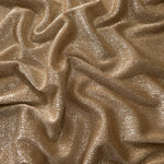 Draped Antique Gold Sheer Glitter Stretch Tulle Fabric showing scattered sparkle across fluid folds for eveningwear and stage looks