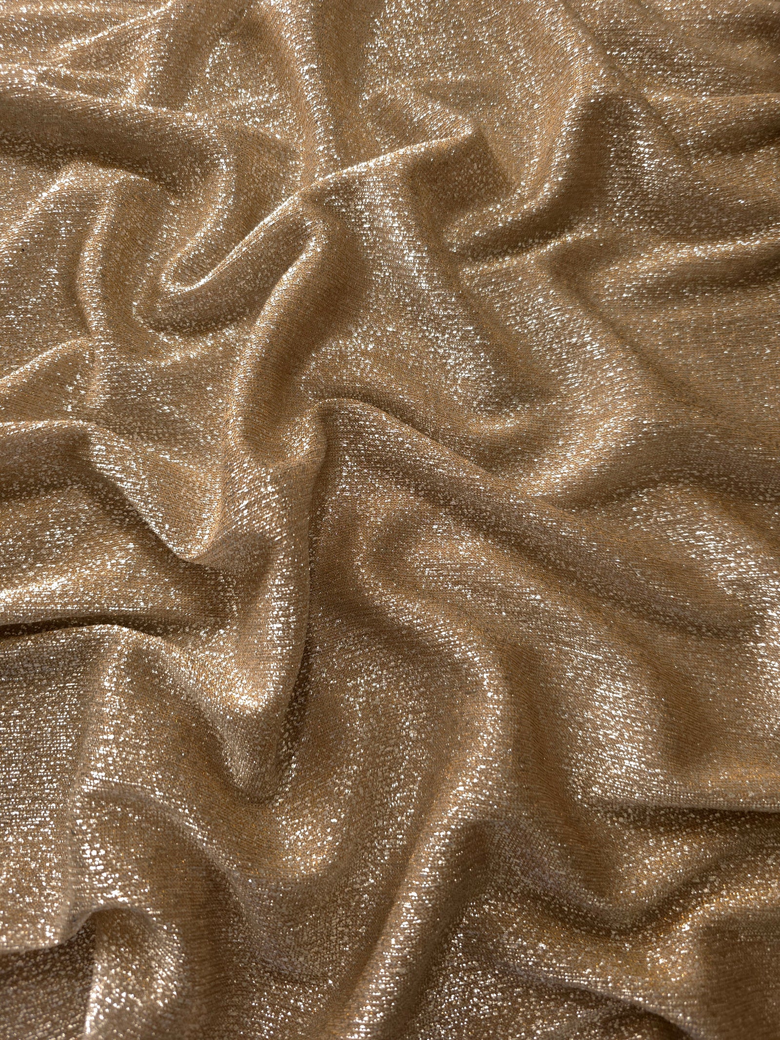 Draped Antique Gold Sheer Glitter Stretch Tulle Fabric showing scattered sparkle across fluid folds for eveningwear and stage looks