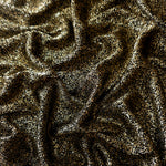 Draped Black Gold Sheer Glitter Stretch Tulle Fabric showing scattered sparkle across fluid folds for eveningwear and stage looks
