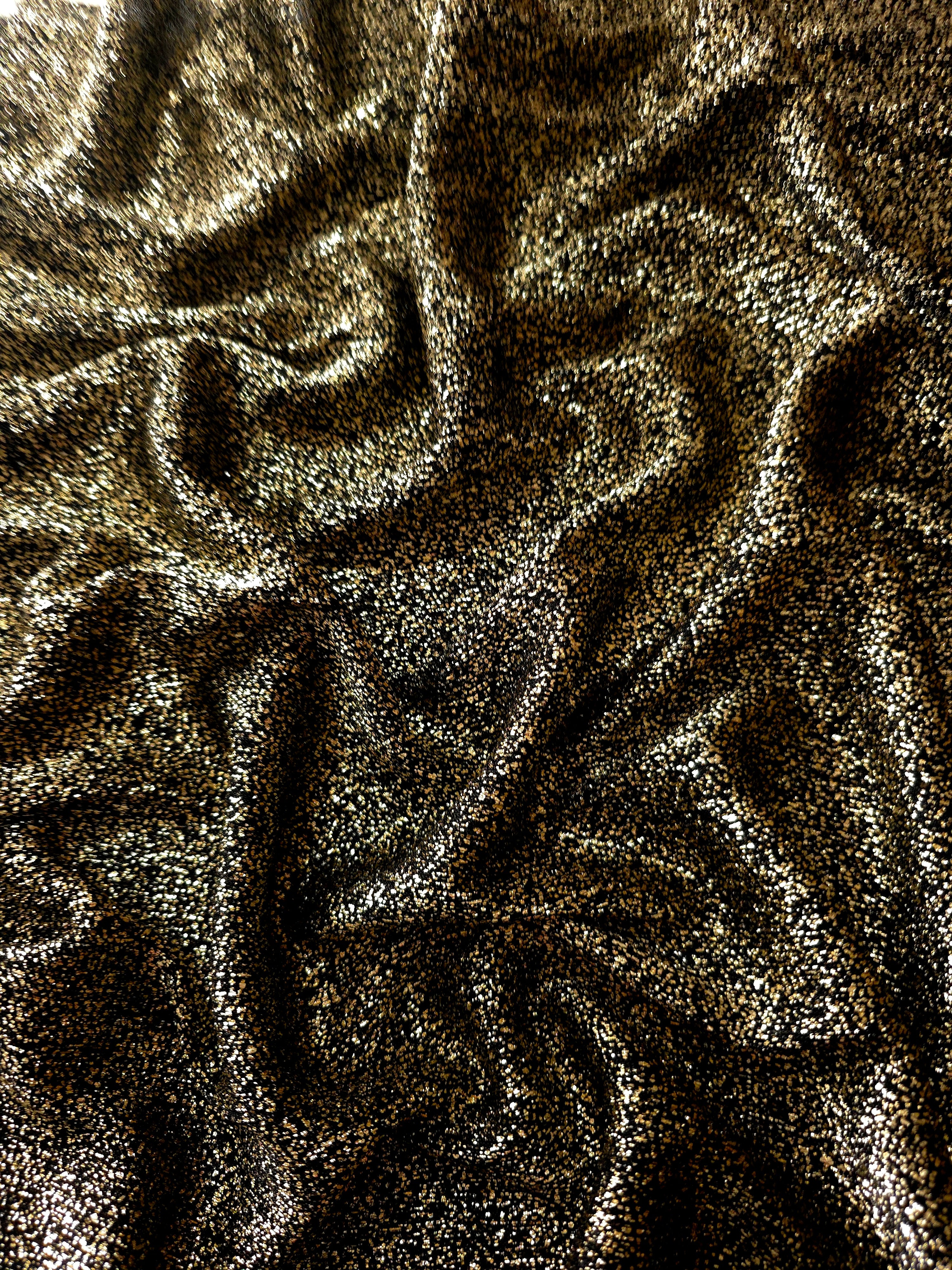 Draped Black Gold Sheer Glitter Stretch Tulle Fabric showing scattered sparkle across fluid folds for eveningwear and stage looks