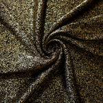 Swirl-draped Black Gold Sheer Glitter Stretch Tulle Fabric capturing reflective sparkle and fluid movement through flexible folds