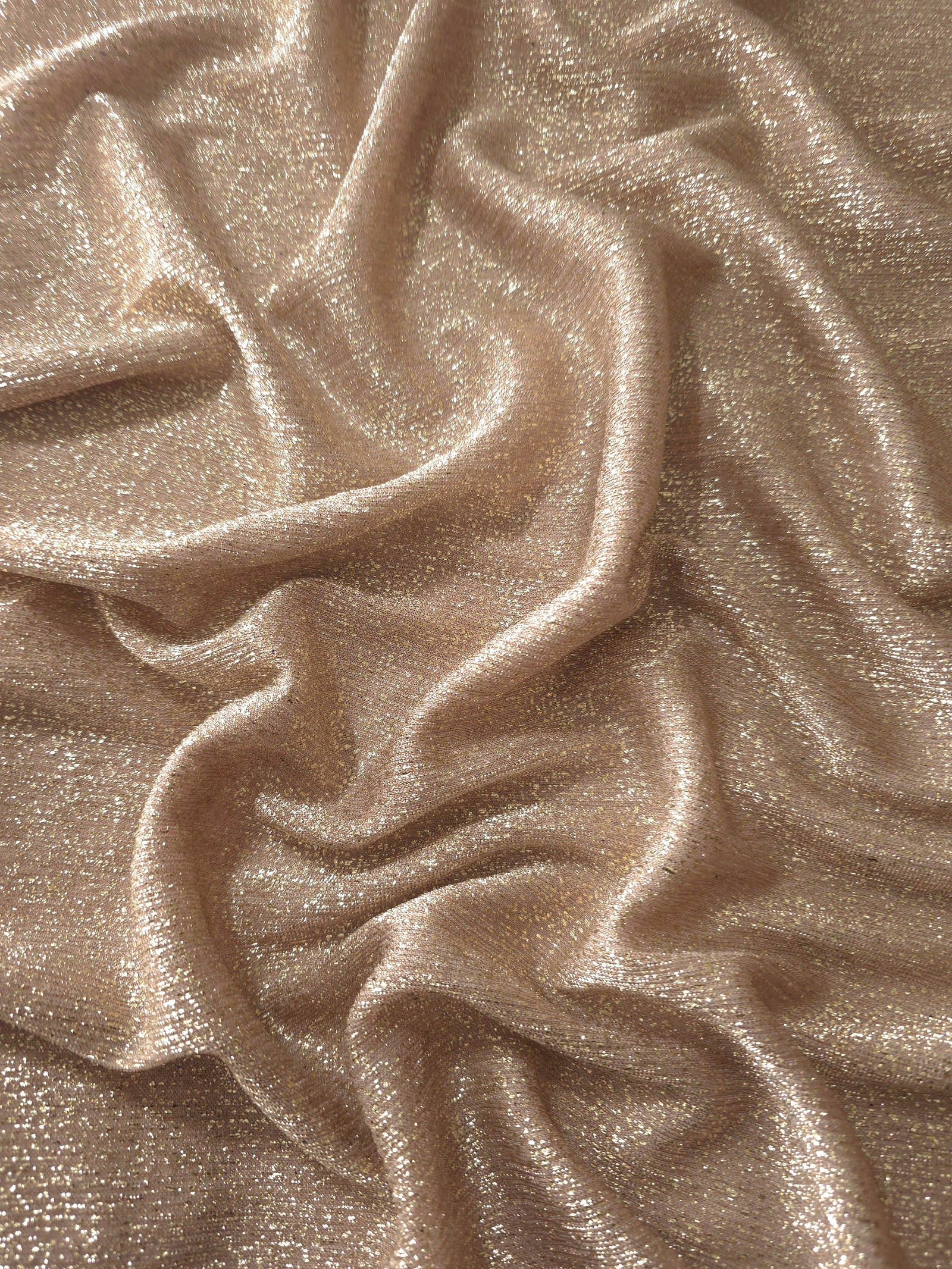 Draped Champagne Beige Sheer Glitter Stretch Tulle Fabric showing scattered sparkle across fluid folds for eveningwear and stage looks