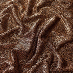 Draped Copper Bronze Sheer Glitter Stretch Tulle Fabric showing scattered sparkle across fluid folds for eveningwear and stage looks