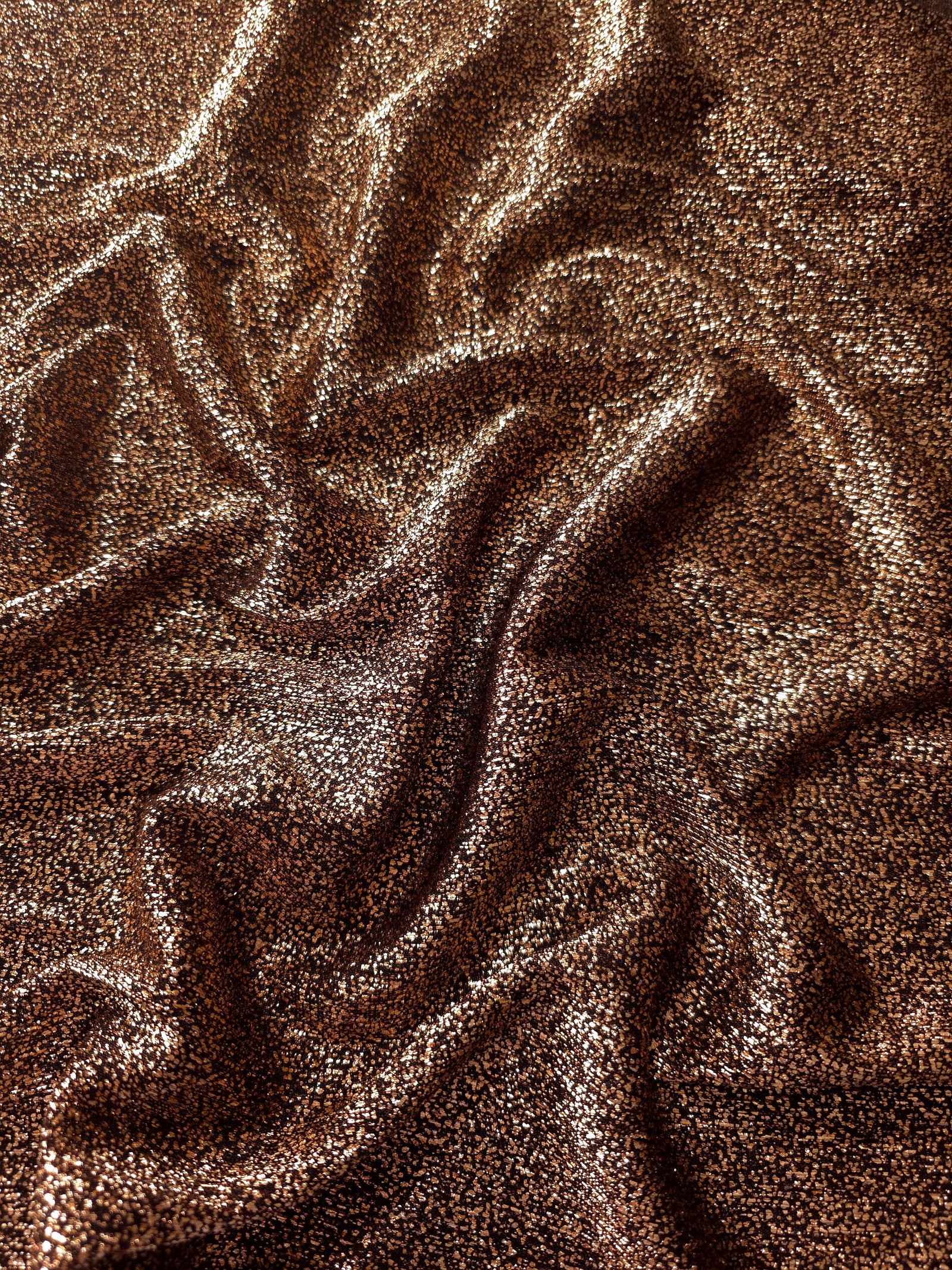 Draped Copper Bronze Sheer Glitter Stretch Tulle Fabric showing scattered sparkle across fluid folds for eveningwear and stage looks