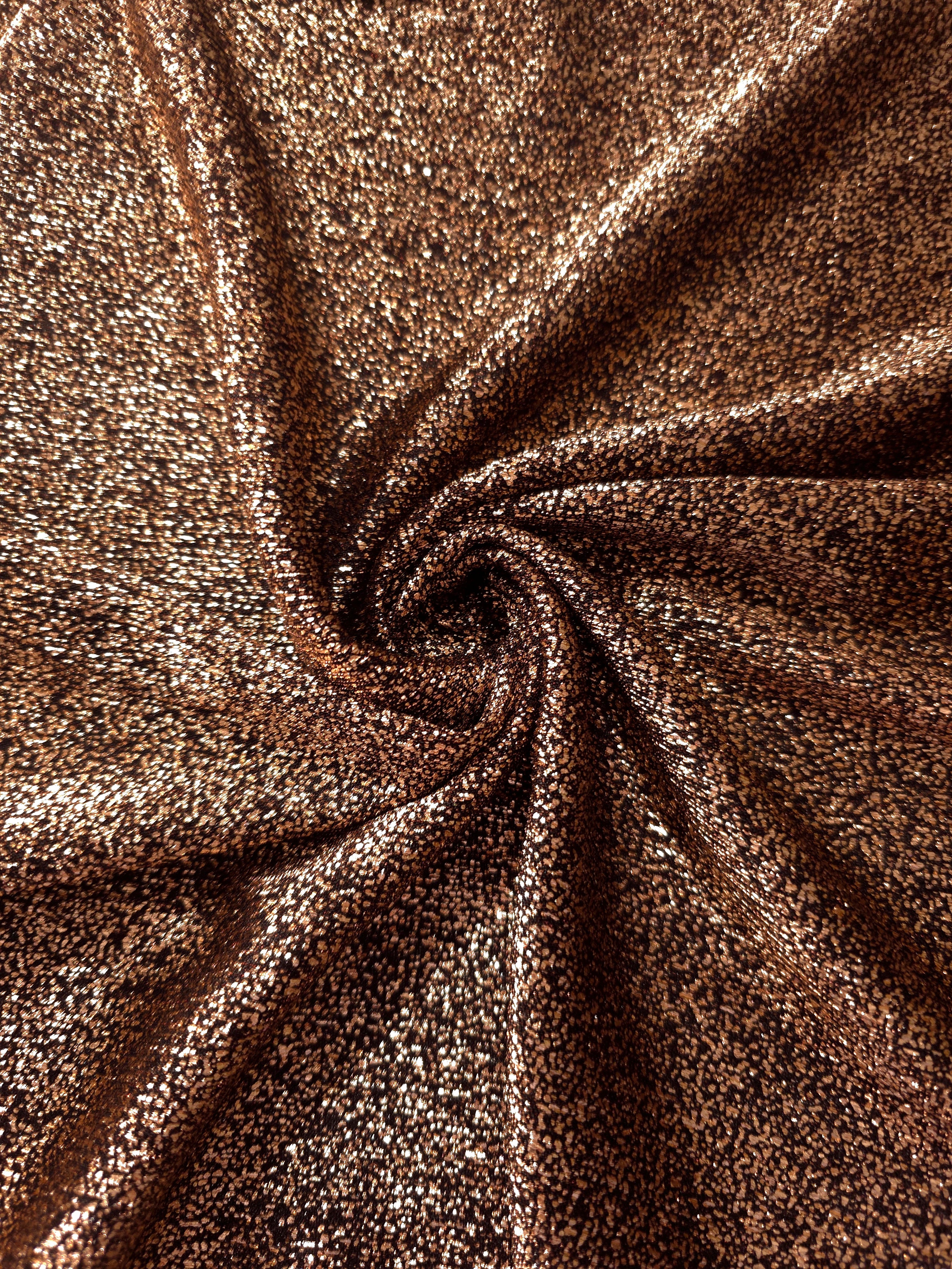 Swirl-draped Copper Bronze Sheer Glitter Stretch Tulle Fabric capturing reflective sparkle and fluid movement through flexible folds