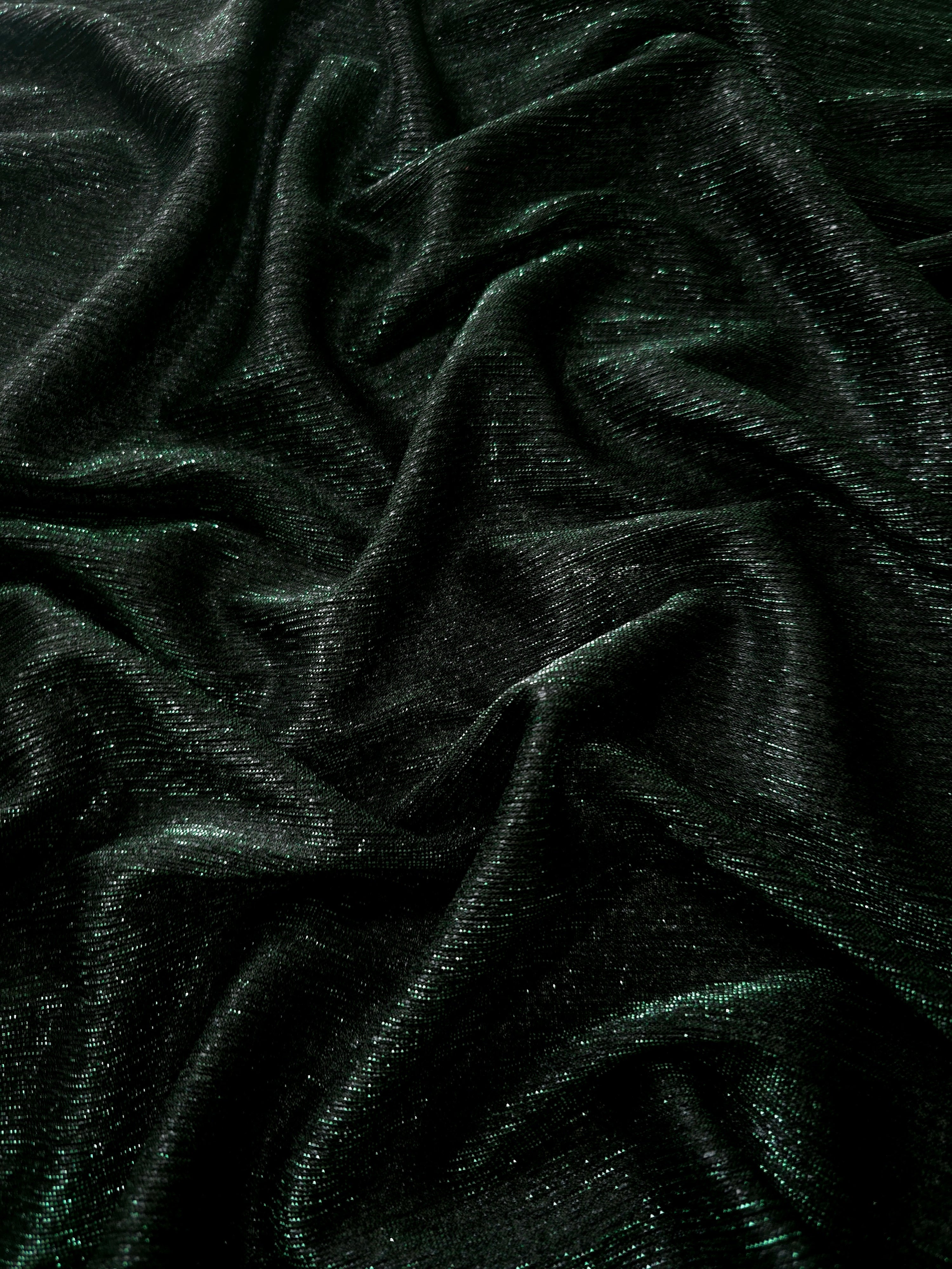 Draped Deep Emerald Sheer Glitter Stretch Tulle Fabric showing scattered sparkle across fluid folds for eveningwear and stage looks