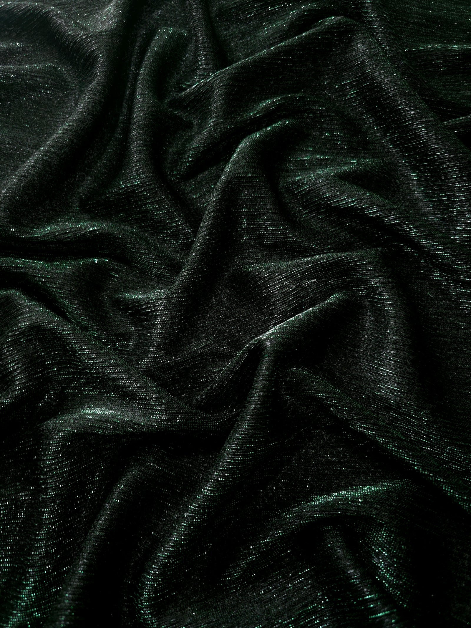 Draped Deep Emerald Sheer Glitter Stretch Tulle Fabric showing scattered sparkle across fluid folds for eveningwear and stage looks