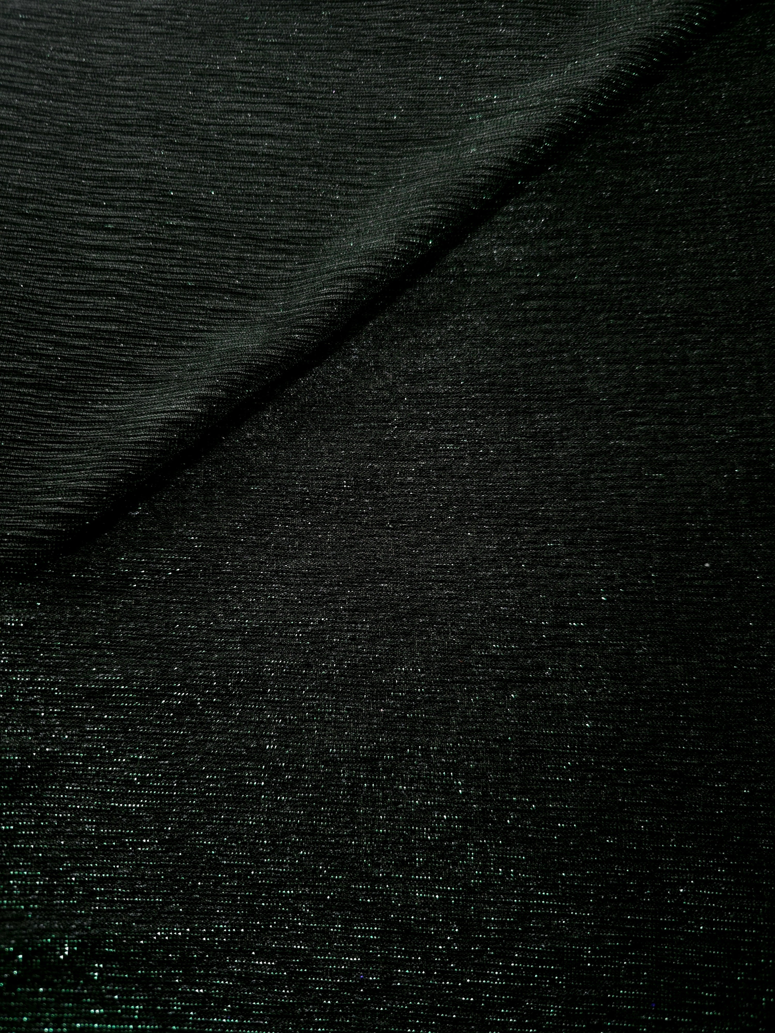Front and back of Deep Emerald Sheer Glitter Stretch Tulle Fabric showing transparent knit construction and flexible 4-way stretch