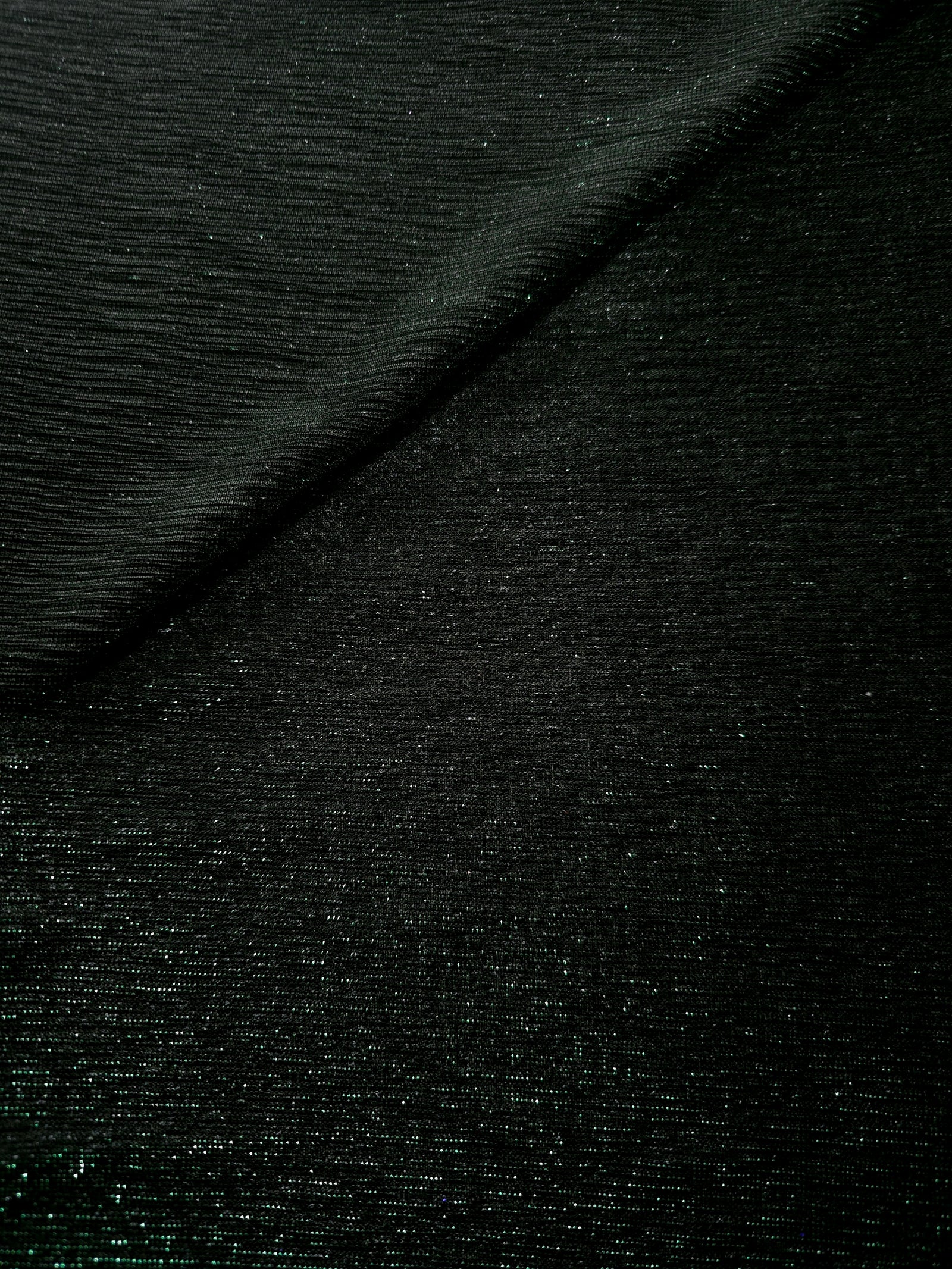 Front and back of Deep Emerald Sheer Glitter Stretch Tulle Fabric showing transparent knit construction and flexible 4-way stretch