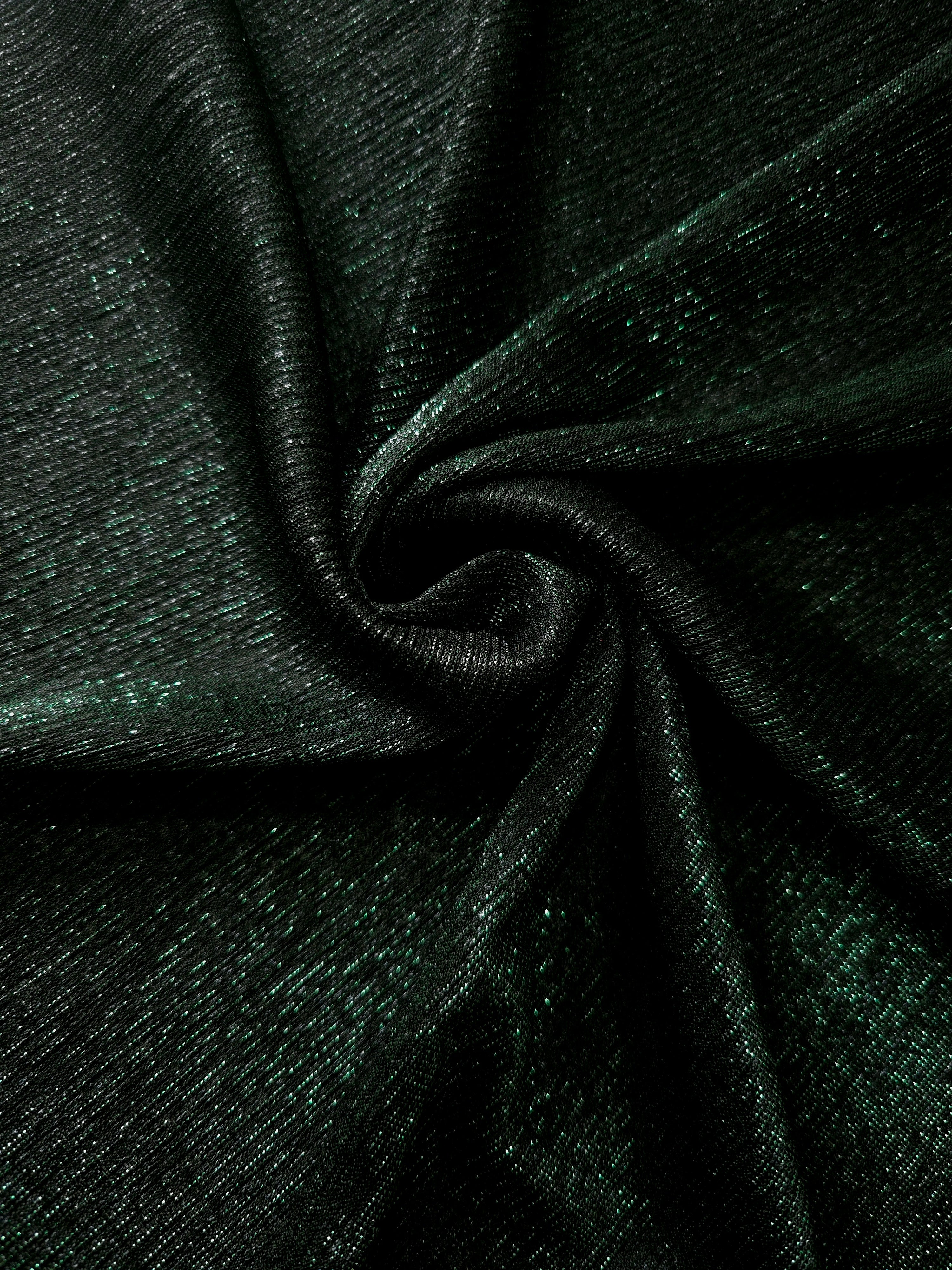 Swirl-draped Deep Emerald Sheer Glitter Stretch Tulle Fabric capturing reflective sparkle and fluid movement through flexible folds