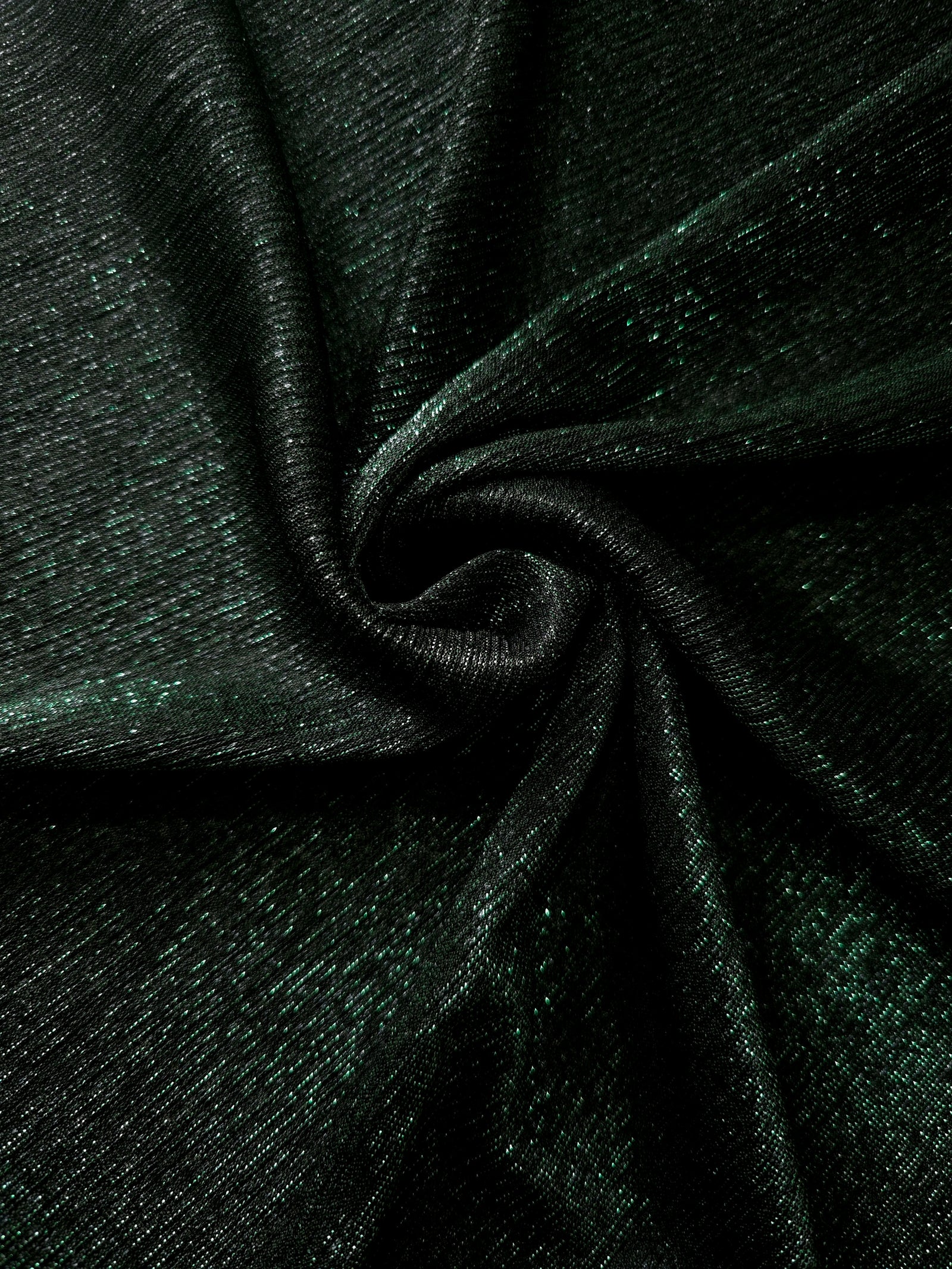 Swirl-draped Deep Emerald Sheer Glitter Stretch Tulle Fabric capturing reflective sparkle and fluid movement through flexible folds