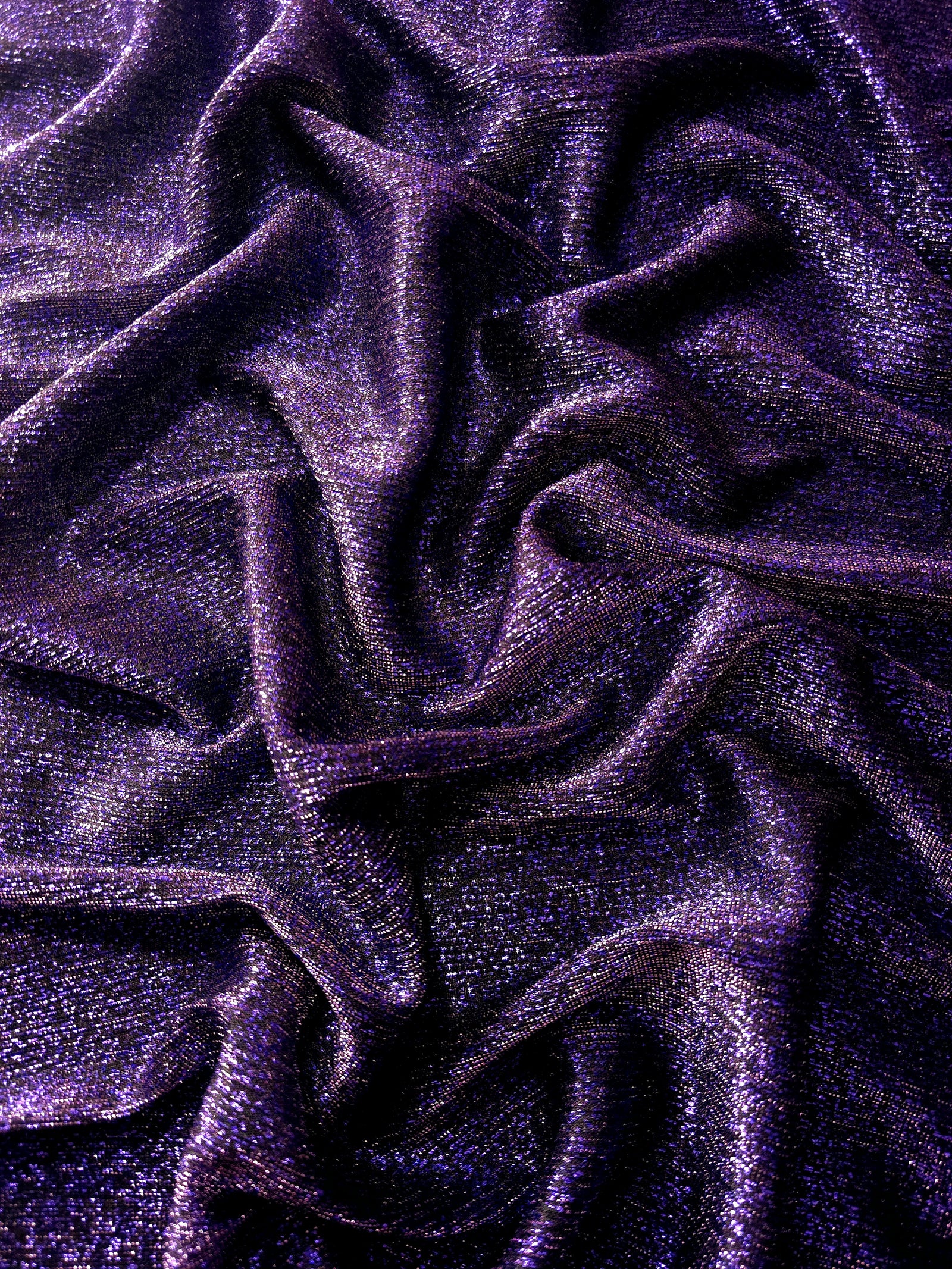 Draped Deep Violet Sheer Glitter Stretch Tulle Fabric showing scattered sparkle across fluid folds for eveningwear and stage looks