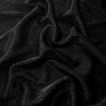 Draped Jet Black Sheer Glitter Stretch Tulle Fabric showing scattered sparkle across fluid folds for eveningwear and stage looks