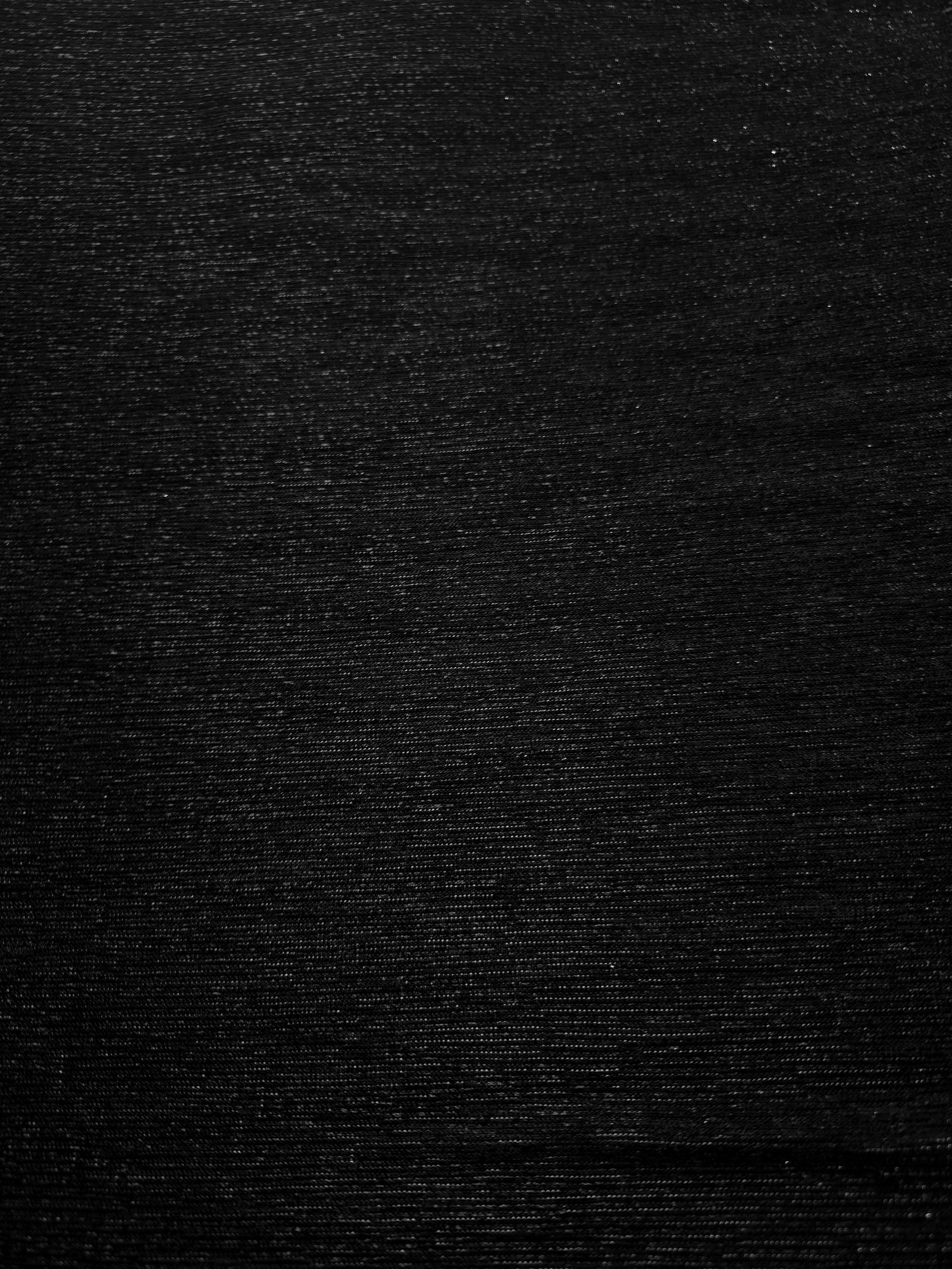 Surface detail of Jet Black Sheer Glitter Stretch Tulle Fabric showing glitter coverage across the fine sheer tulle base