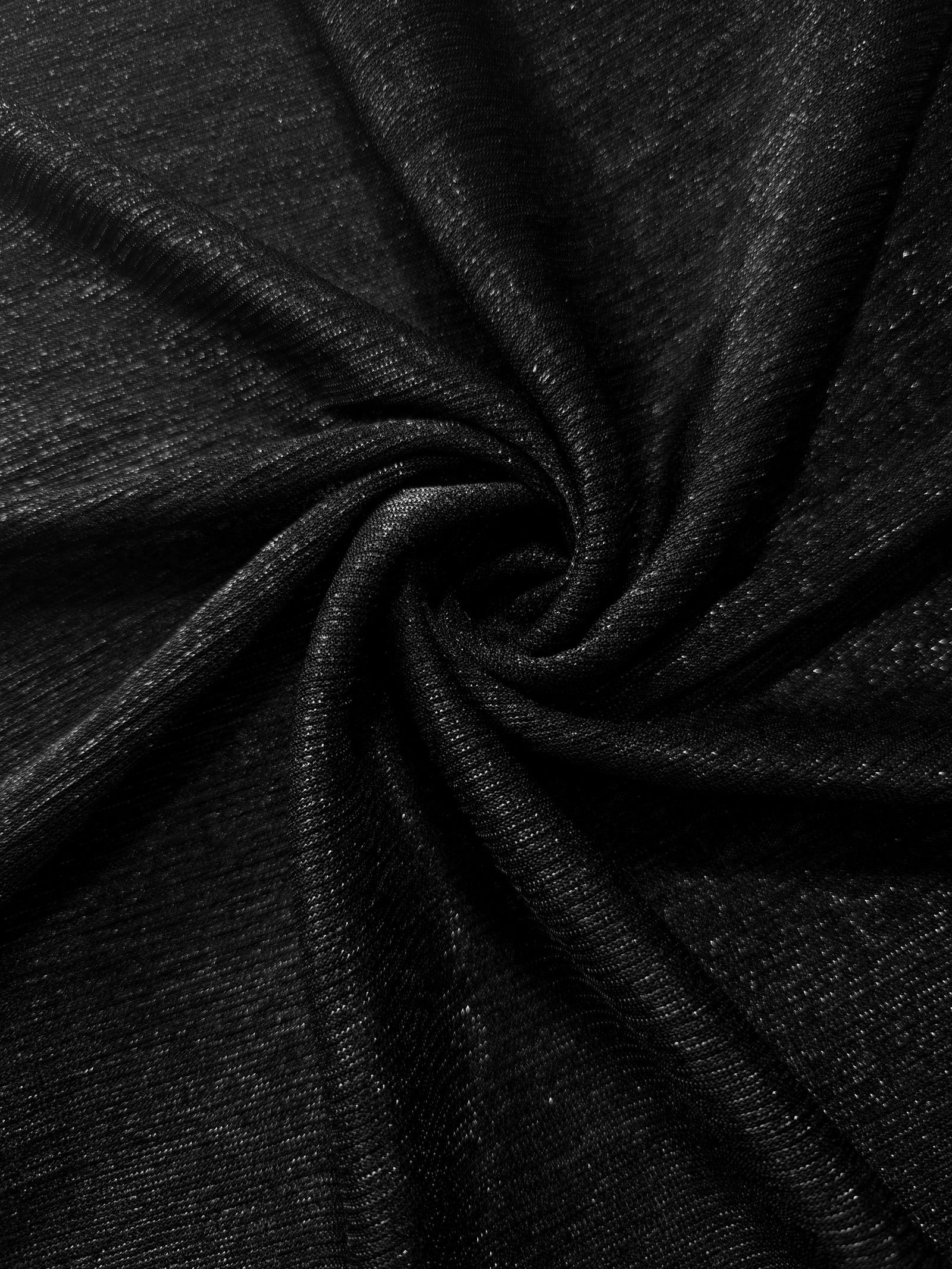 Swirl-draped Jet Black Sheer Glitter Stretch Tulle Fabric capturing reflective sparkle and fluid movement through flexible folds