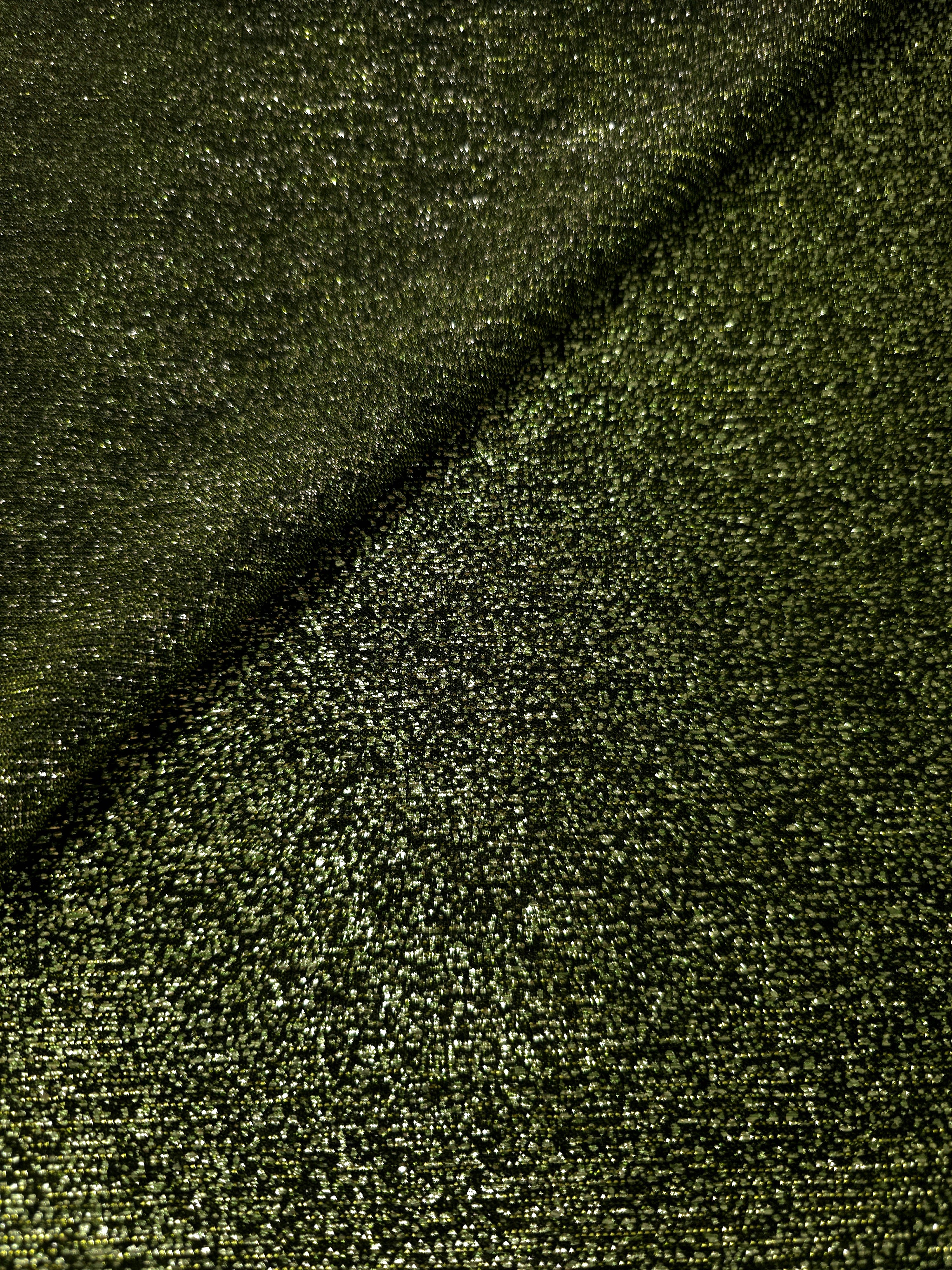 Draped Olive Green Sheer Glitter Stretch Tulle Fabric showing scattered sparkle across fluid folds for eveningwear and stage looks