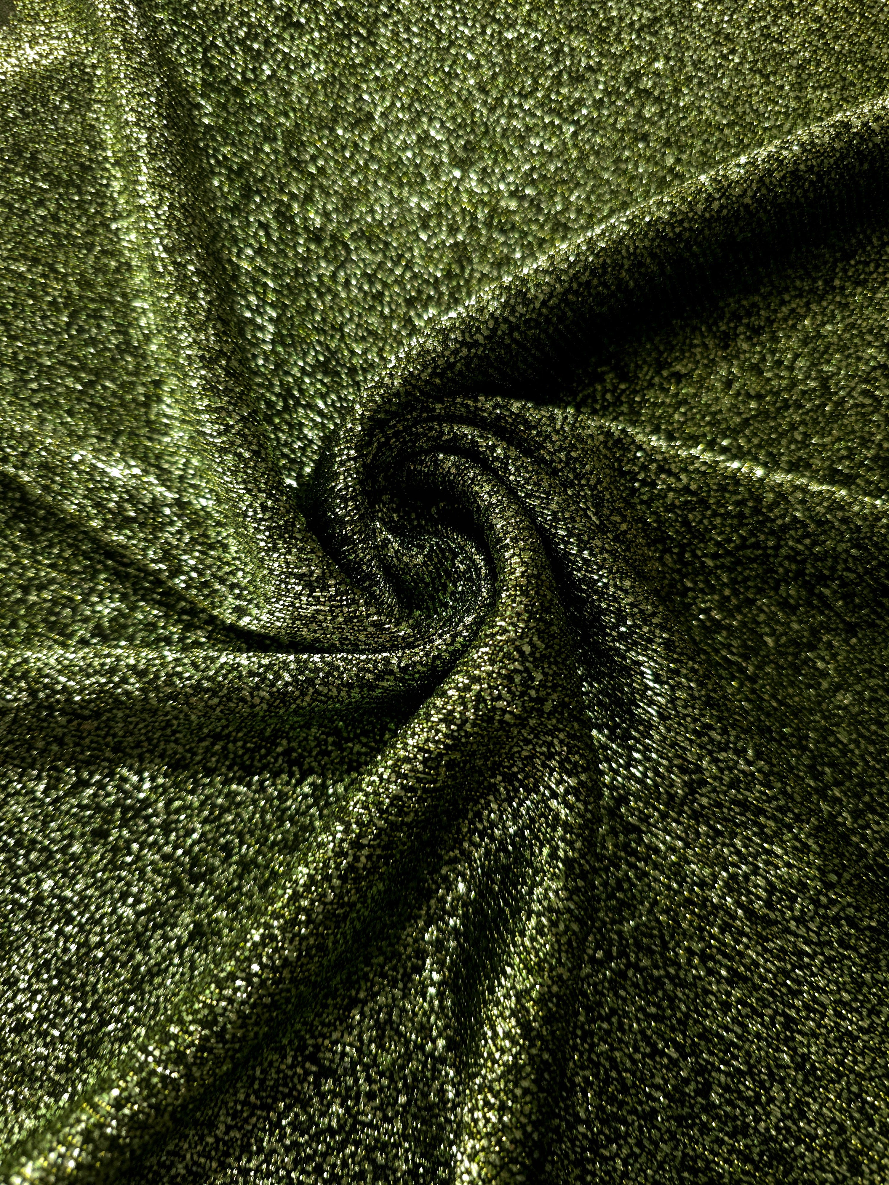 Swirl-draped Olive Green Sheer Glitter Stretch Tulle Fabric capturing reflective sparkle and fluid movement through flexible folds